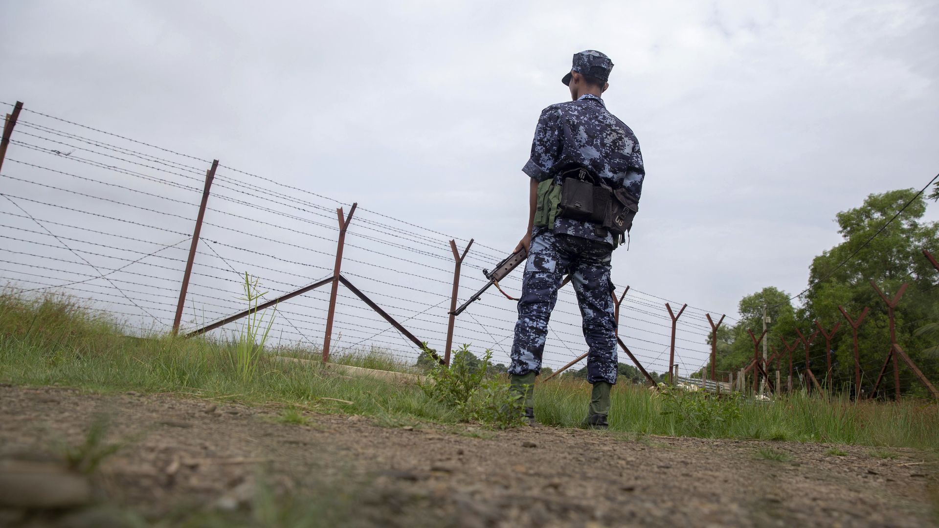 A Myanmar guard stands by a fence.