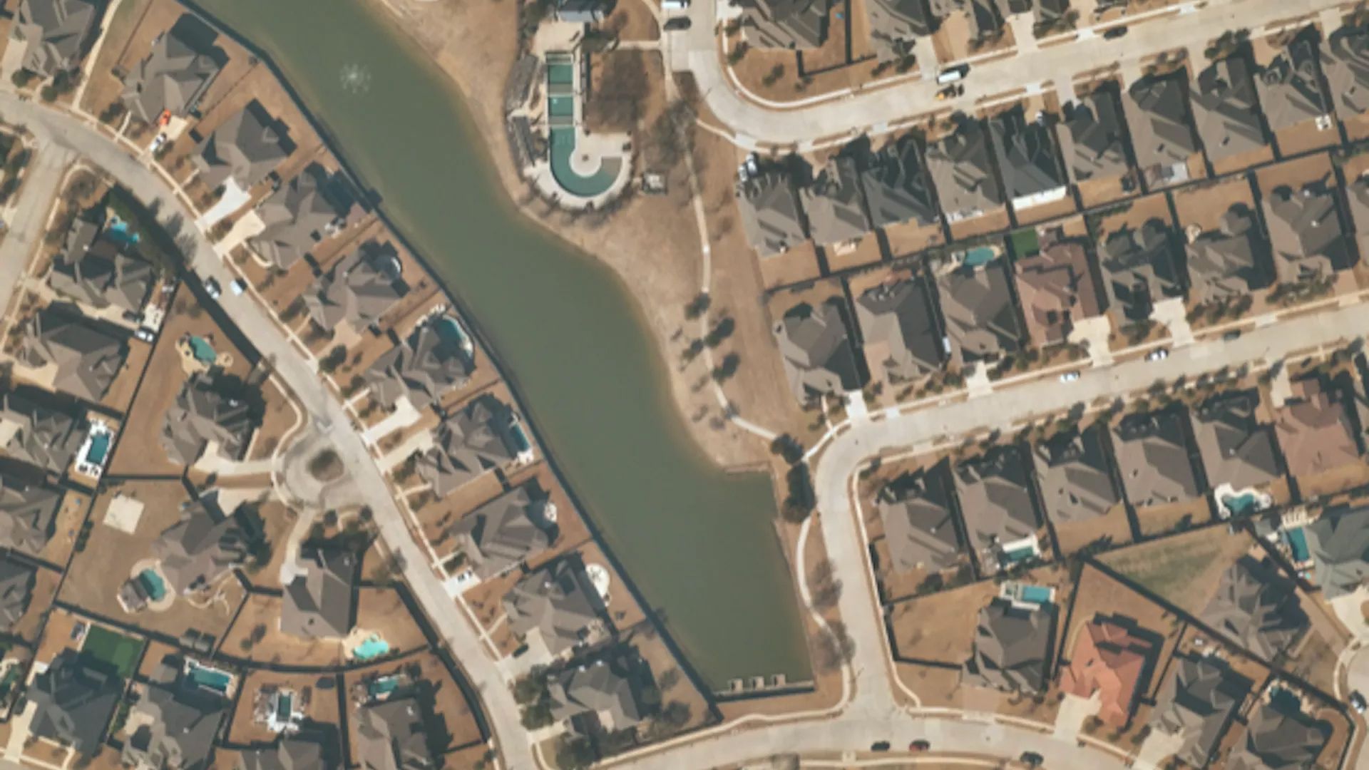 Drone photo of a neighborhood surrounding a lake.