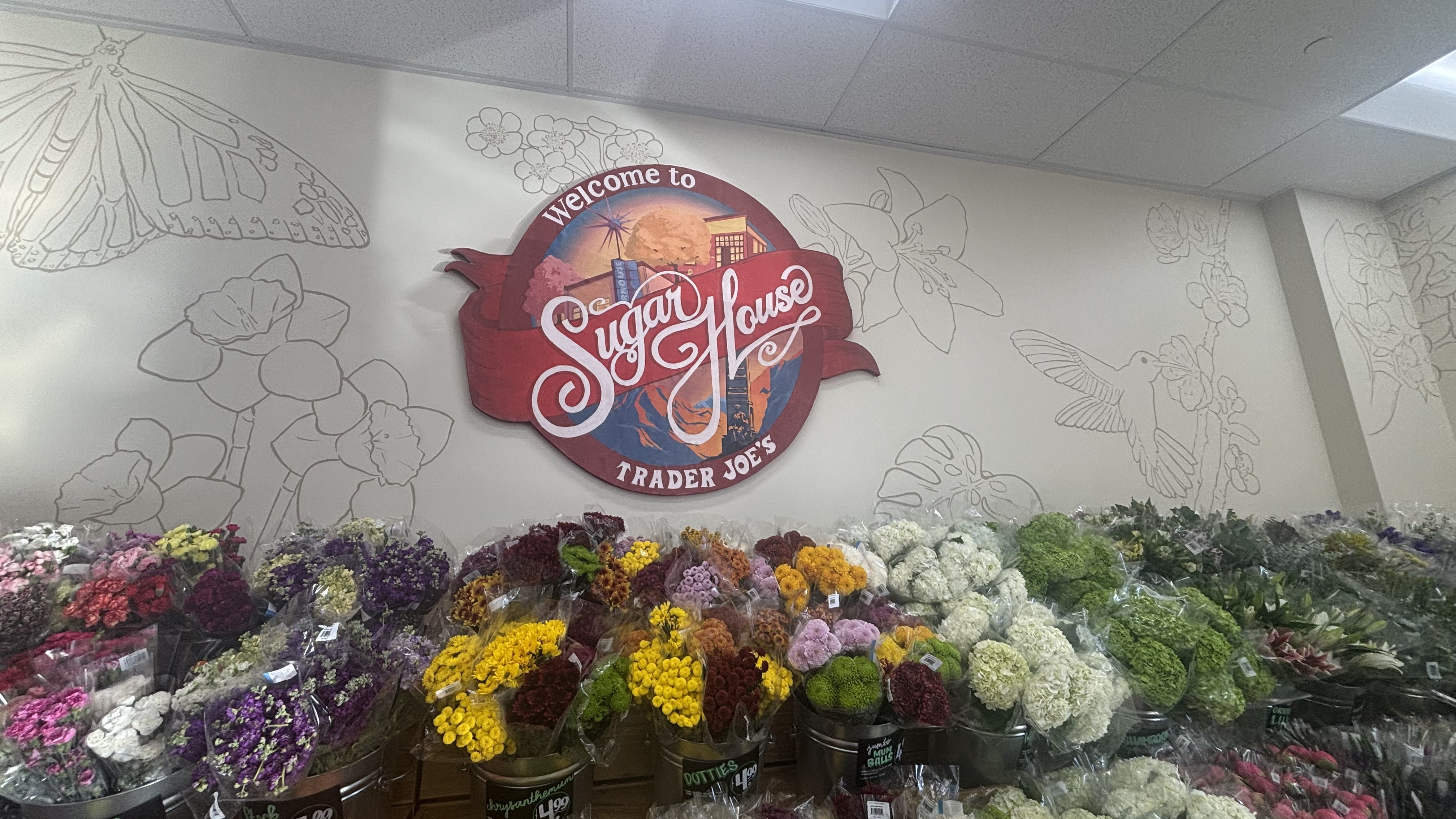 Sugar House Trader Joe's art display next to flowers.