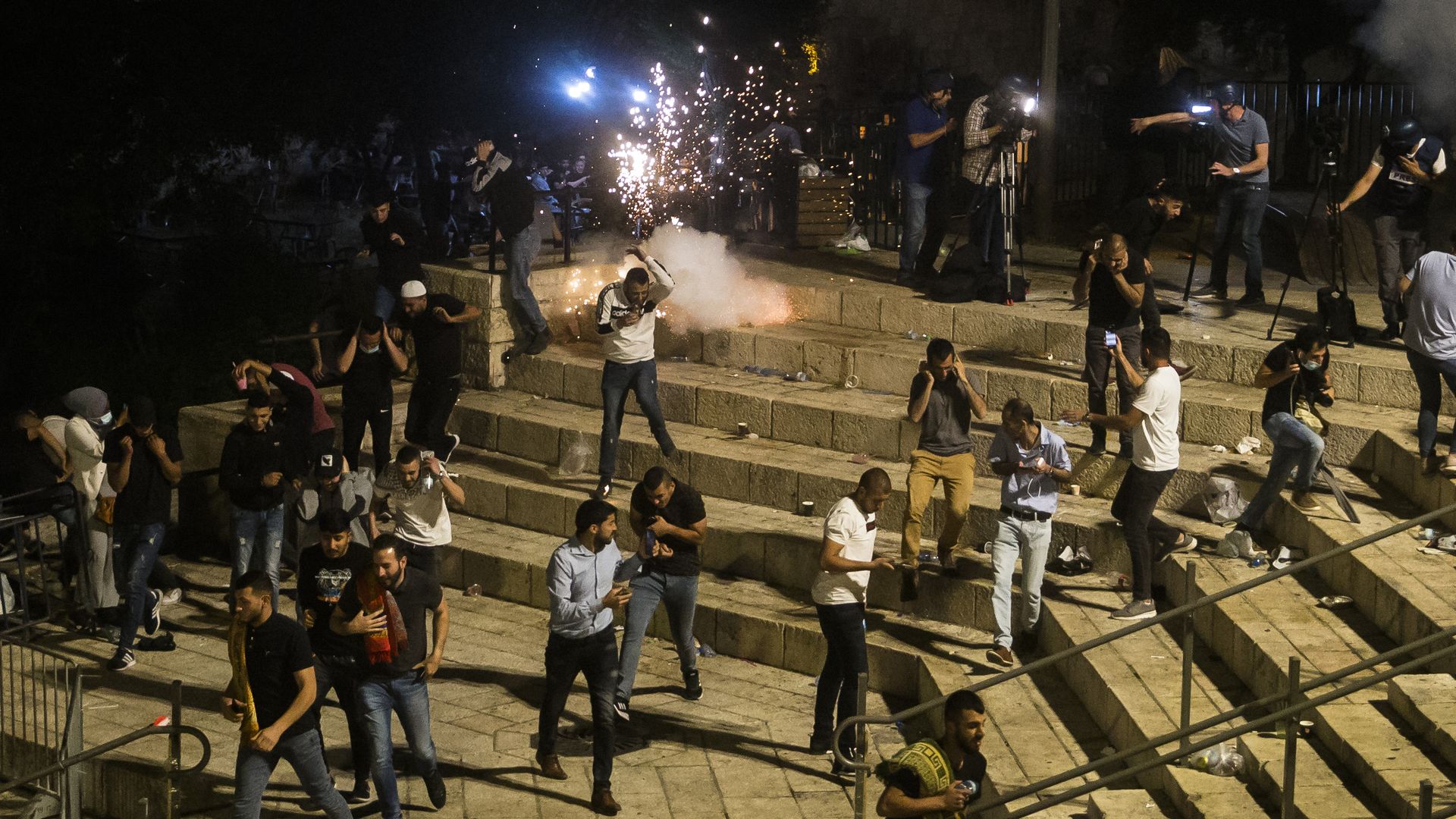 Palestinians escape from a stun grenade fired by Israeli police officers during clashes at Damascus Gate during the holy month of Ramadan on May 8, 2021 in Jerusalem, Israel. 