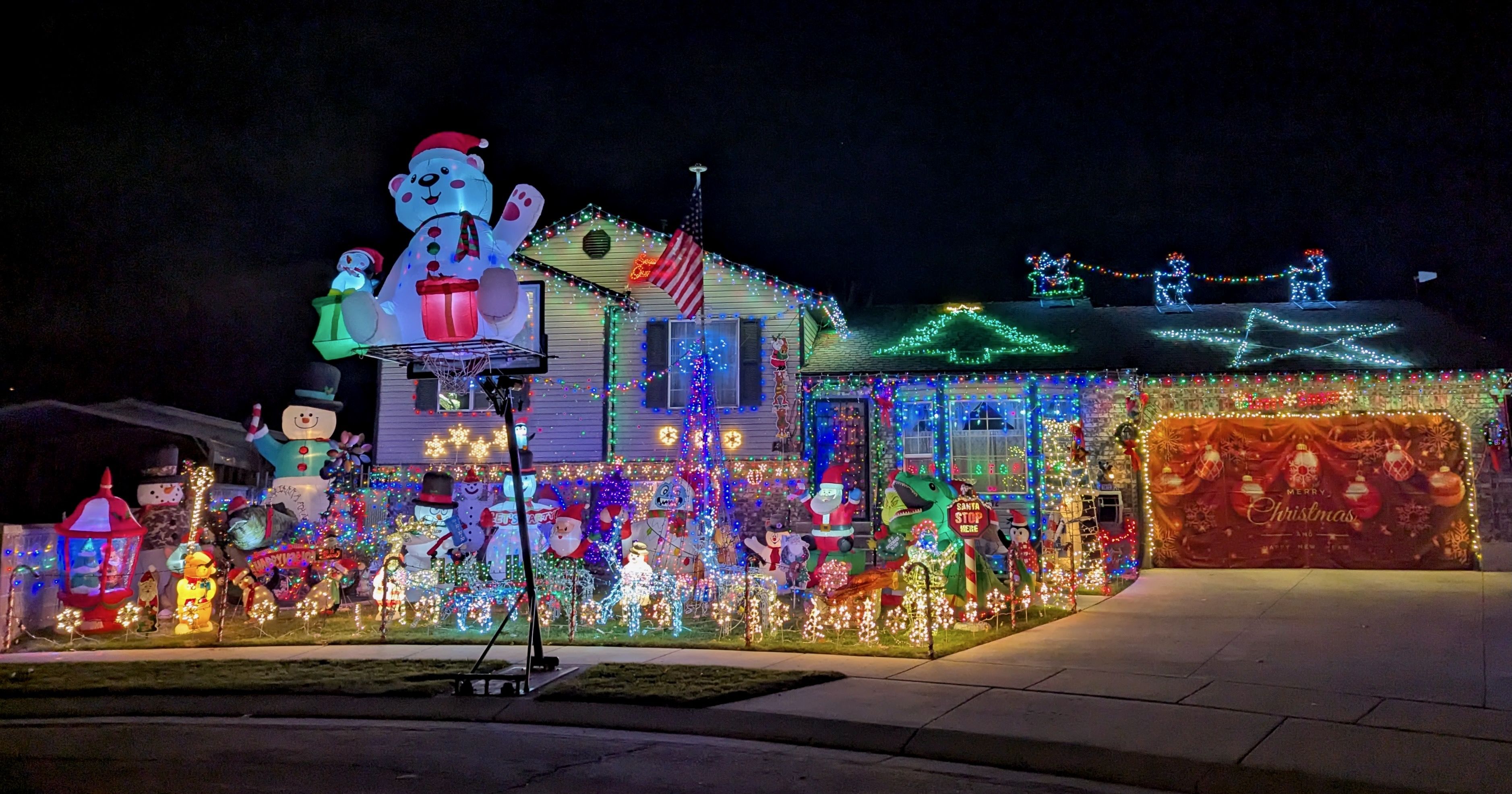 A lot of figurines and inflatable decorations with lights at a residential home