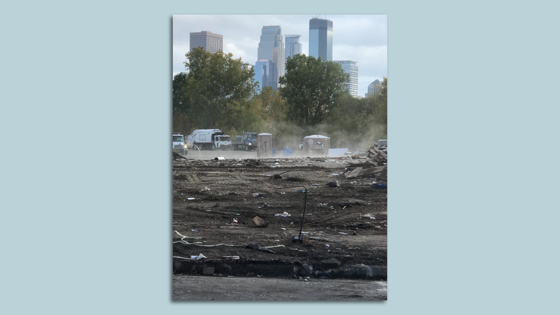 A cleared site where an encampment was, with the downtown skyline in the background 