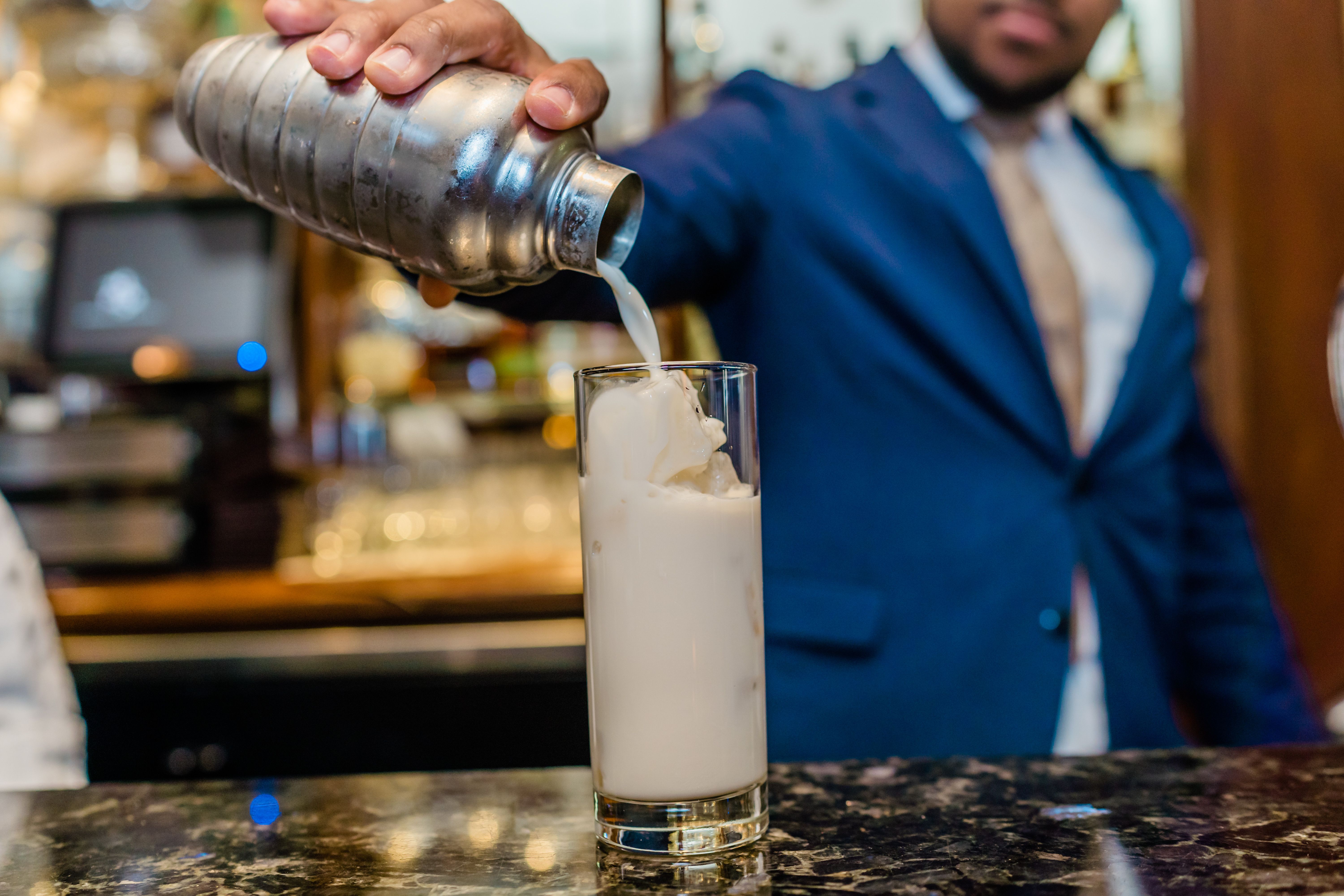 Photo shows a bartender making a brandy milk punch