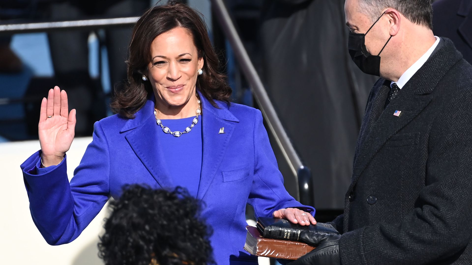 Kamala Harris holds her right hand up as she takes the oath of office. Her left hand is placed atop two Bibles.