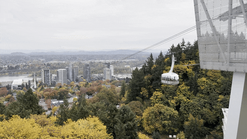 Animated gif of an aerial tram approaching its top terminus with a wide view of the city below.