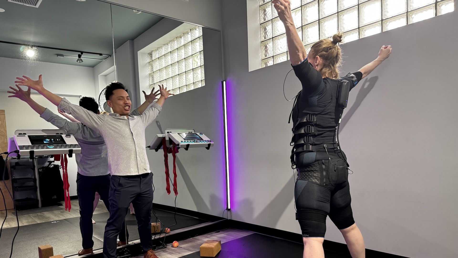 Man with outstretched arms facing a woman in an all black suit with outstretched arms.