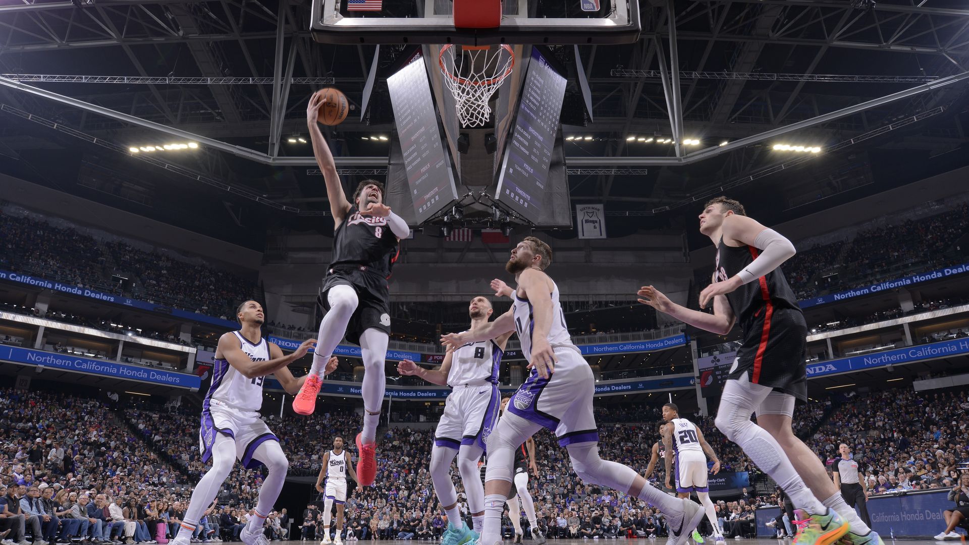 Deni Avdija, a player for the Portland Trail Blazers, take the ball to the hoop surrounded by players for the Sacramento Kings in an NBA game.