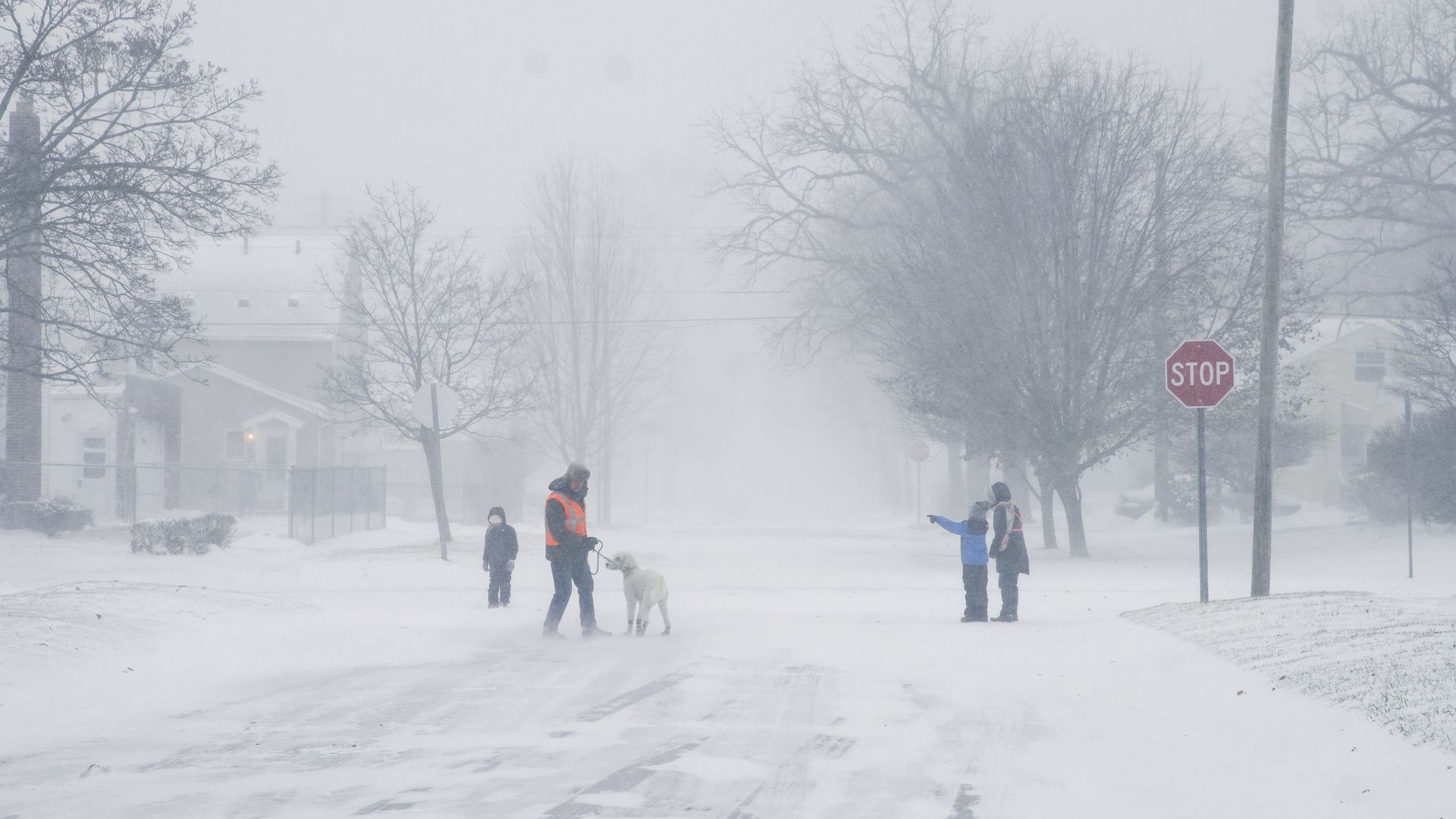 A family walks and runs during a winter snow storm affecting most of the USA, in Flint, MI on December 23, 2022. 