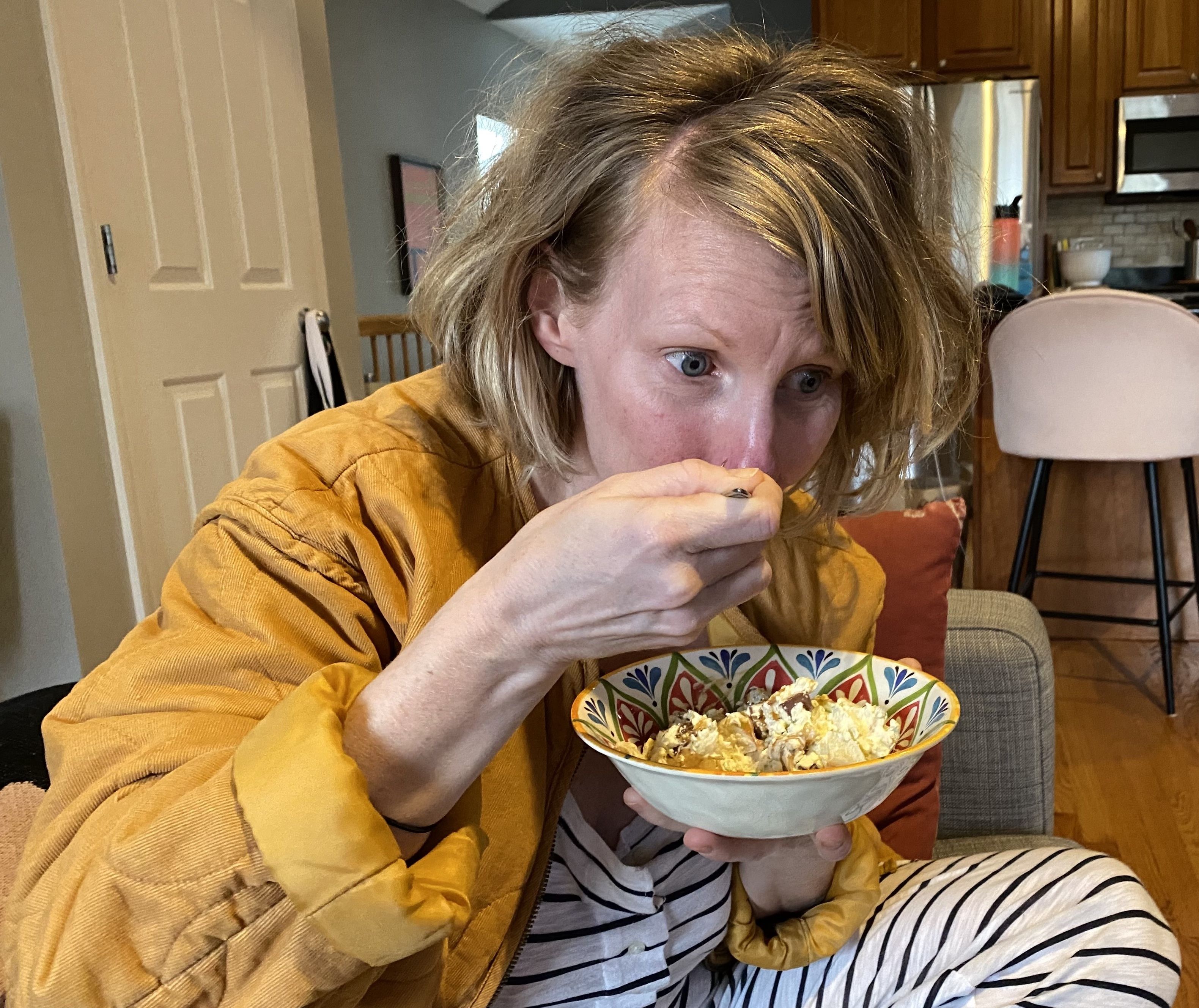 Photo of a woman on a couch eating a bowl of food 