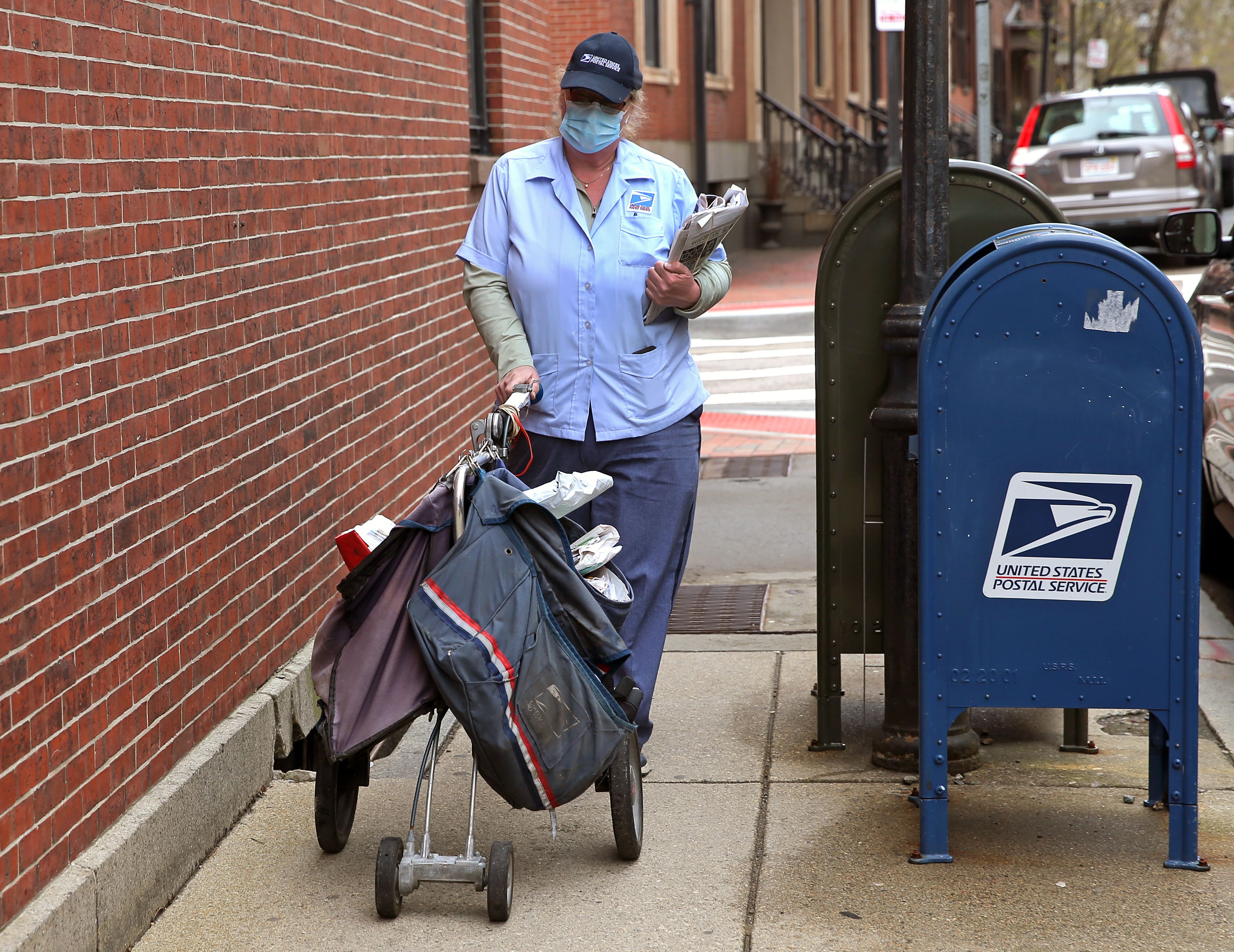 A USPS postal worker wears mask while making deliveries in Beacon Hill in Boston 