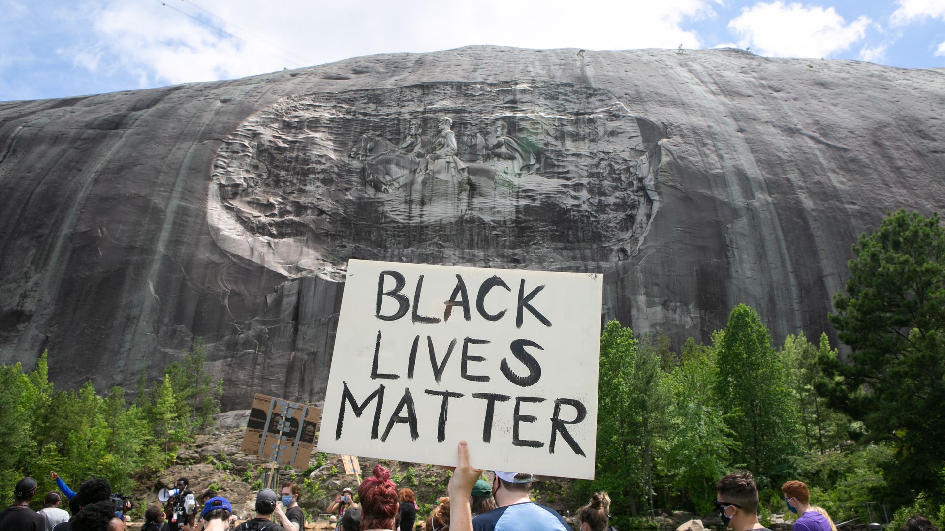 An activist holds a Black Lives Matter sign in front of Stone Mountain's sculpture of Confederate generals during a protest