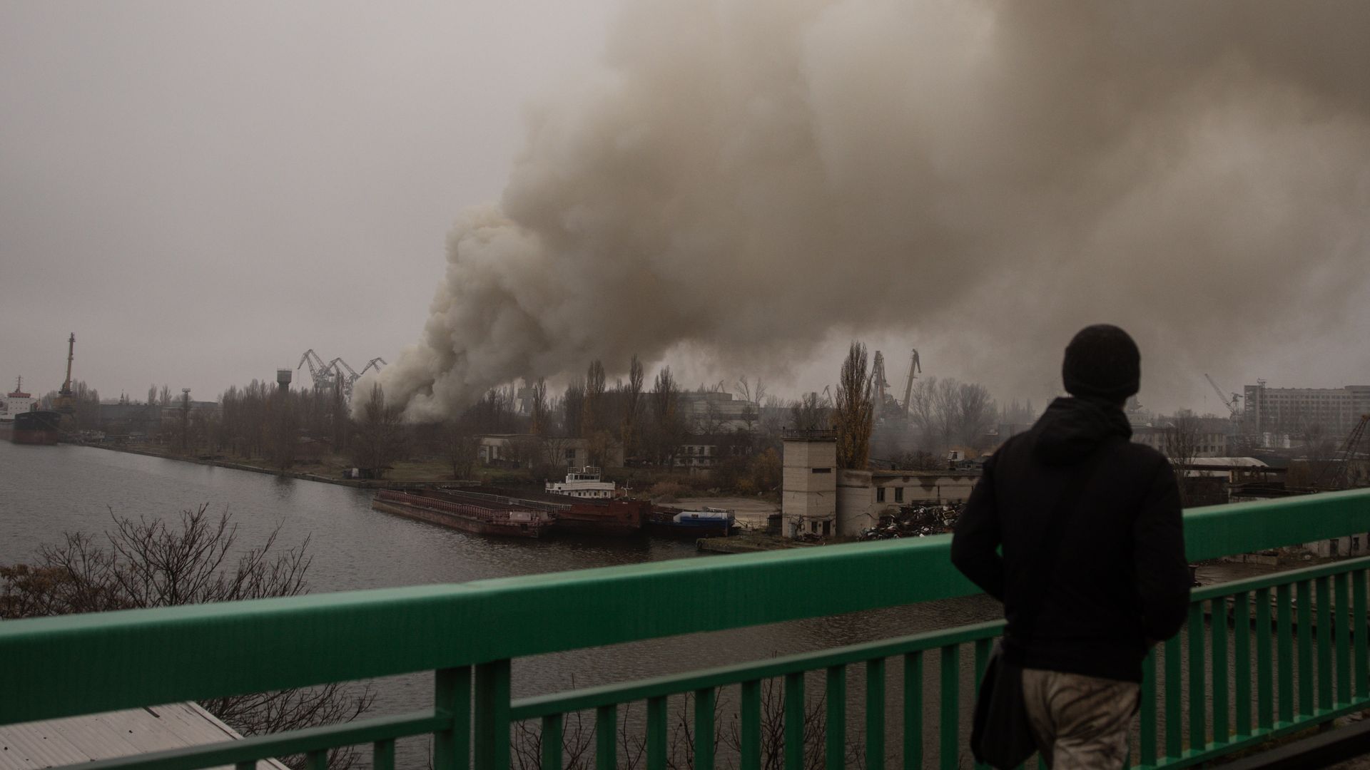 A man looks at smoke rising from a Russian strike in the Kherson ship yards on November 24, 2022 in Kherson, Ukraine.