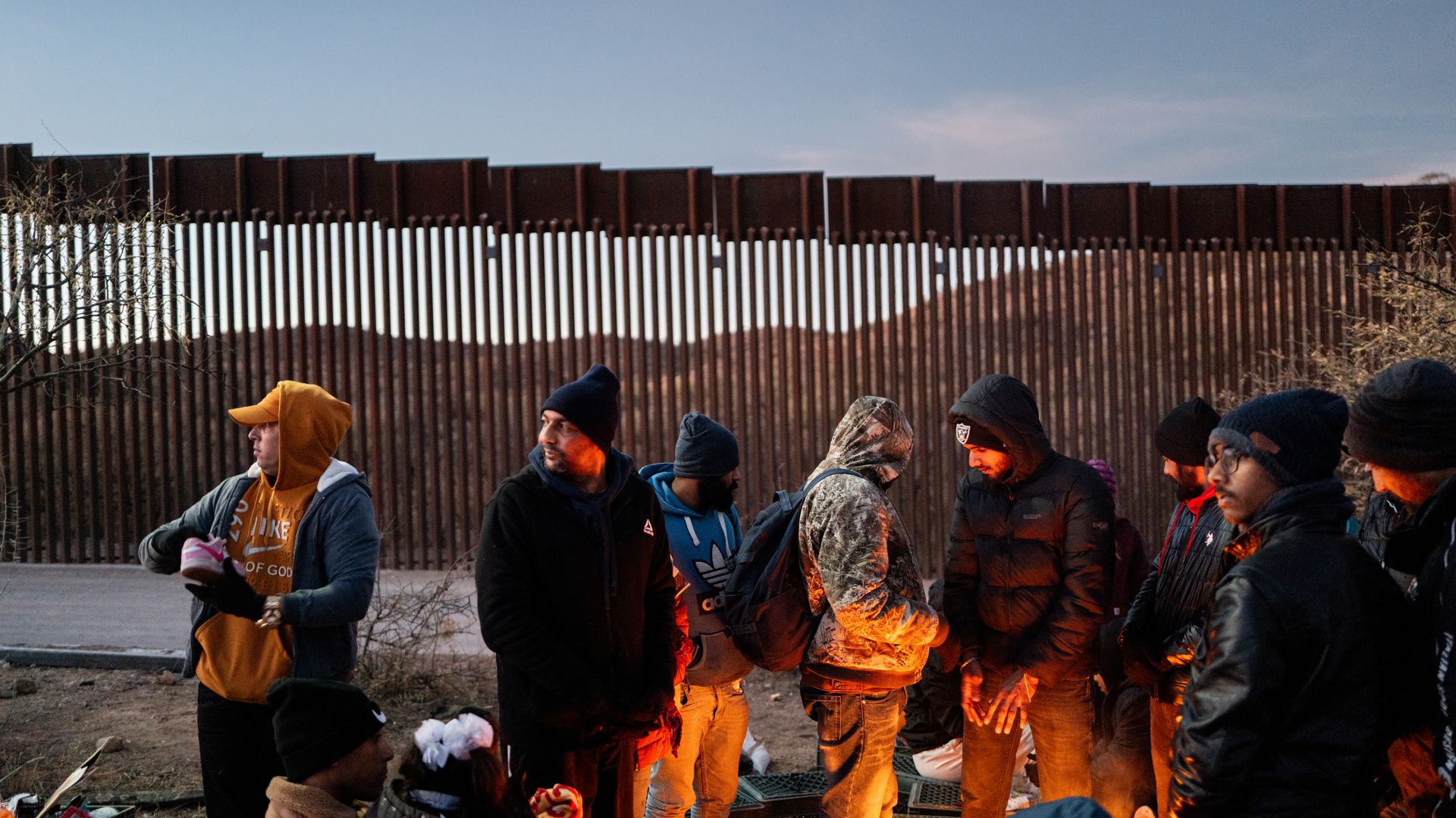Migrants seeking asylum from Mexico, India and Ecuador keep warm by a fire while waiting to be apprehended by U.S. Customs and Border Patrol officers after crossing over a section of border wall into the U.S. on January 05, 2025 in Ruby, Arizona.
