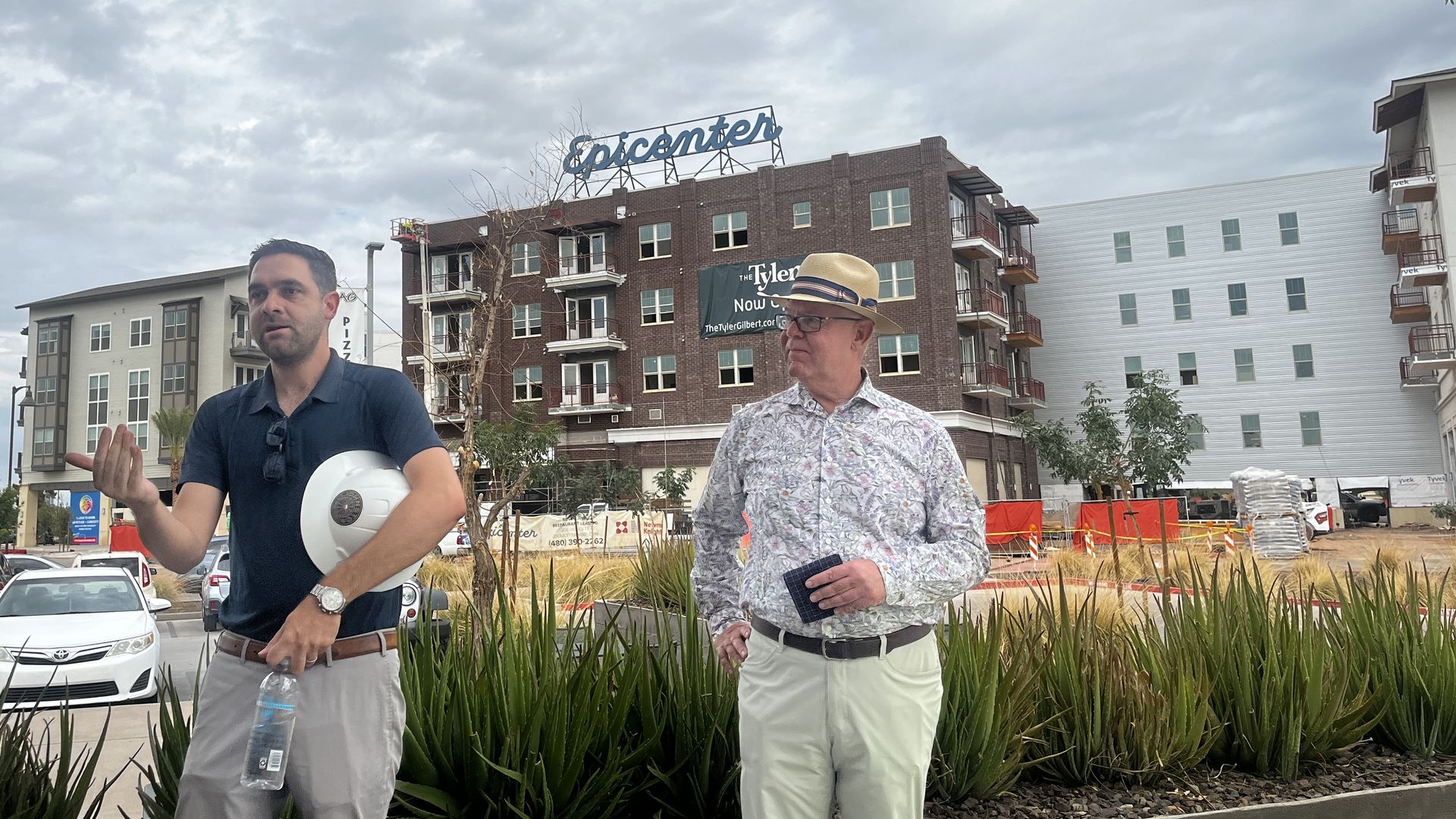 Two men stand in front of a building with a sign that reads, "Epicenter."