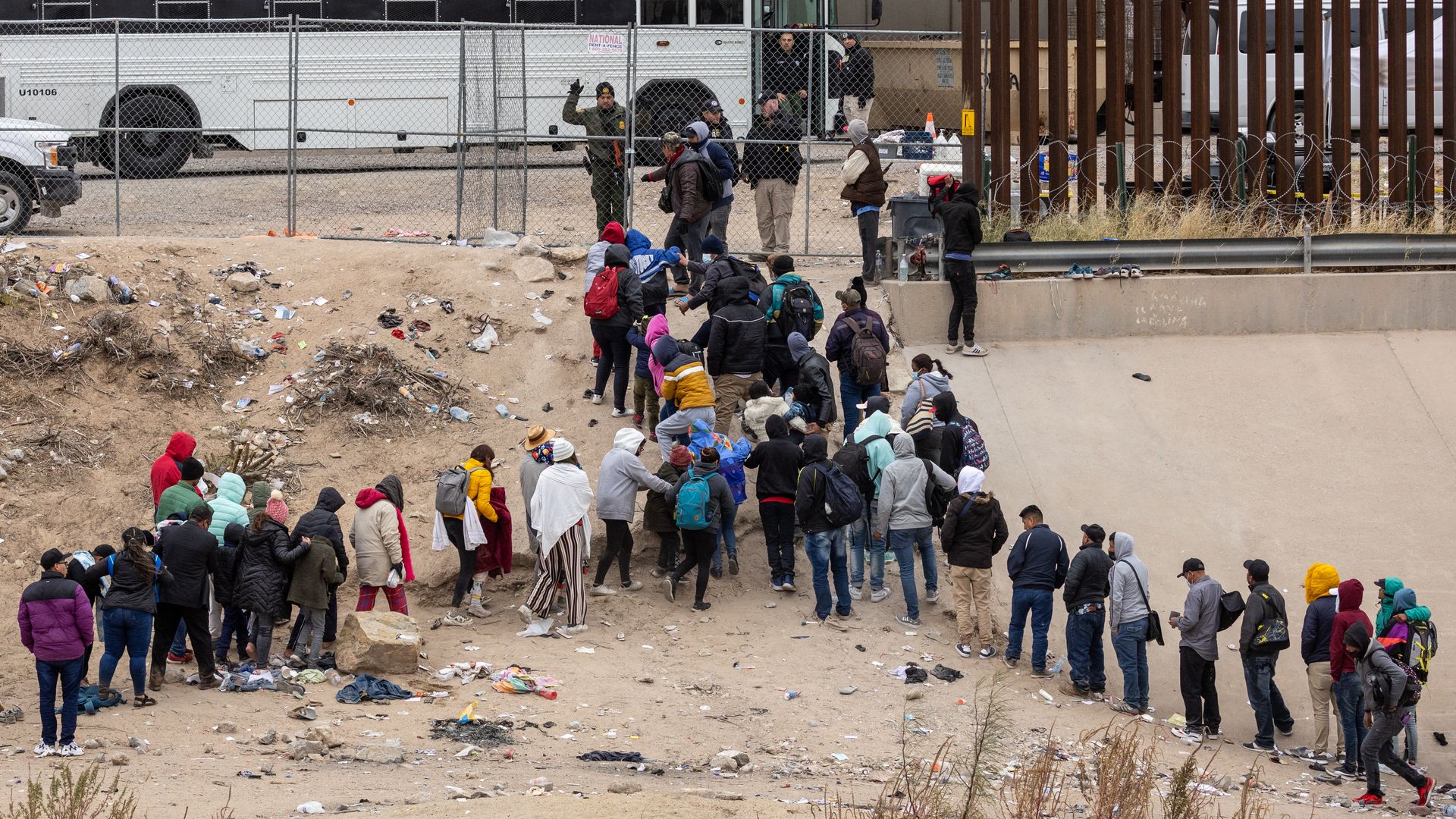 Photo of migrants lined up at a fence