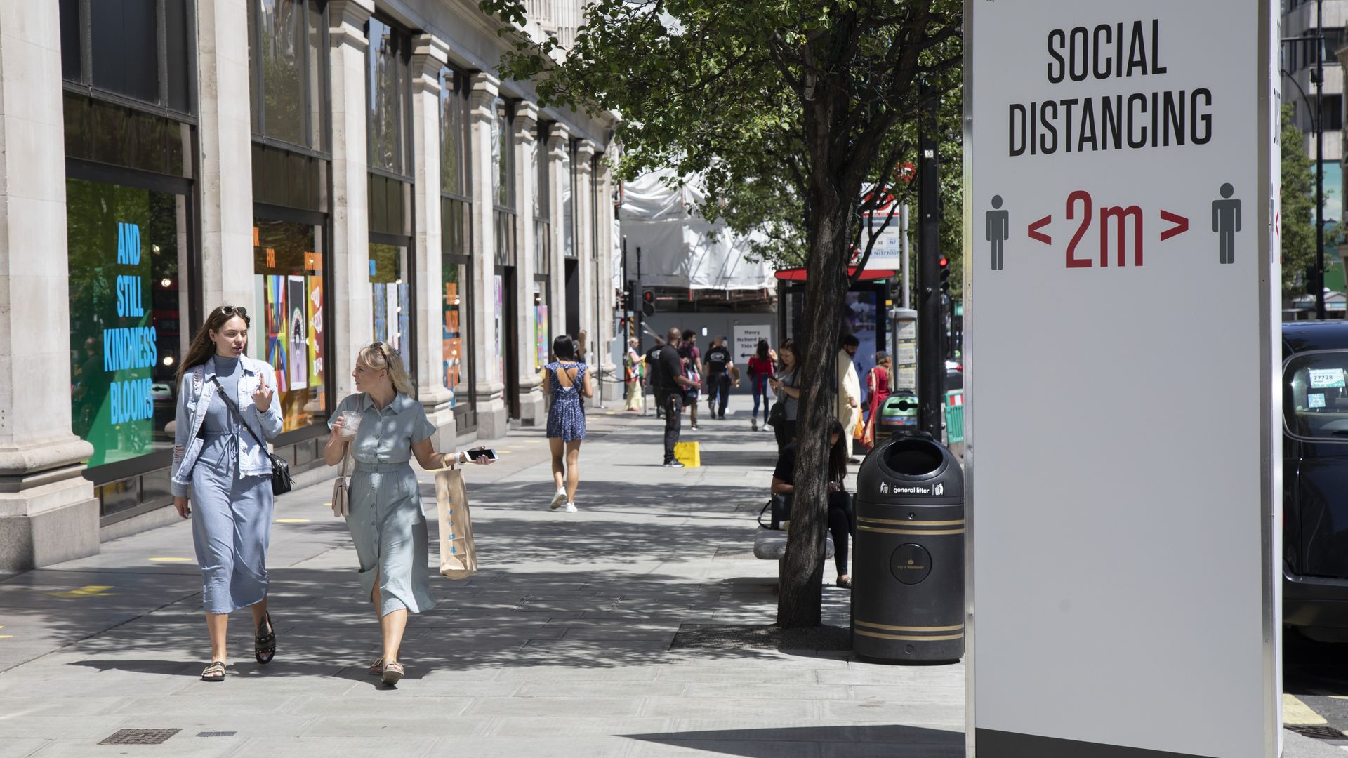 People walking past a social distancing sign on June 22 in London.