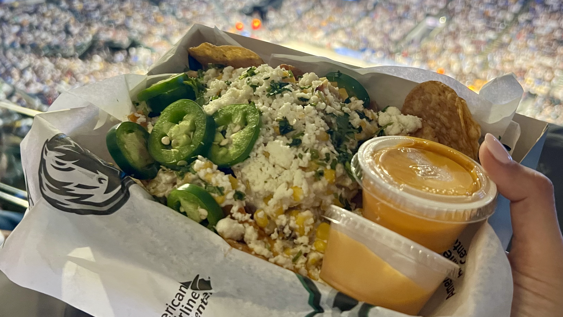 A tray of nacho chips, cheese, corn and jalapenos