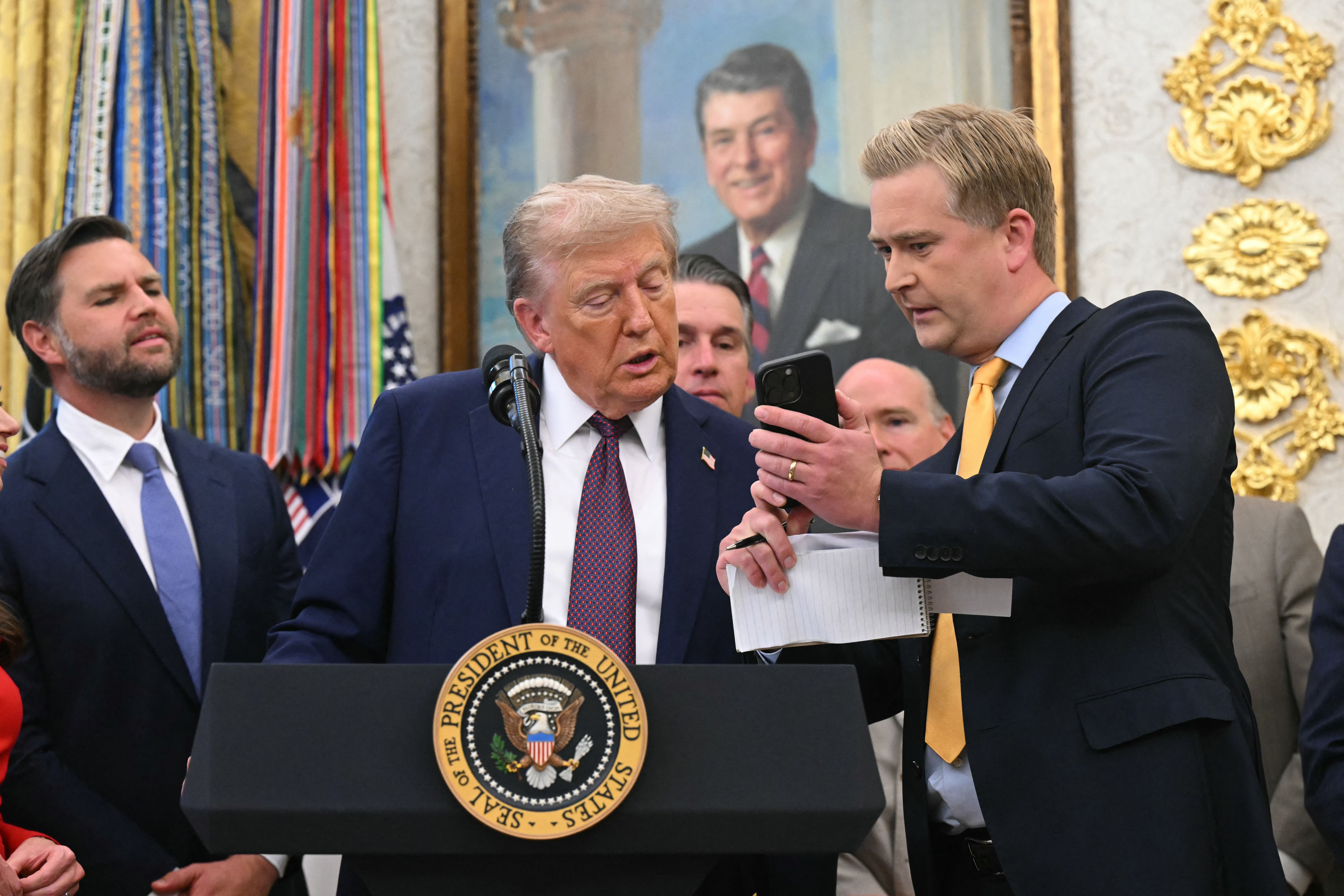 Fox News reporter Peter Doocy shows Trump a video on his phone at Tuesday's press conference.
