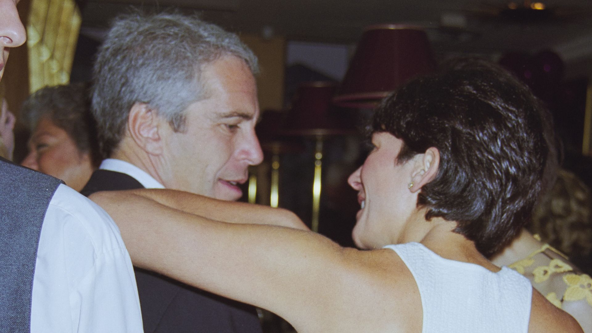 Jeffrey Epstein and Ghislaine Maxwell photographed from behind. Her arm is on his shoulder. 