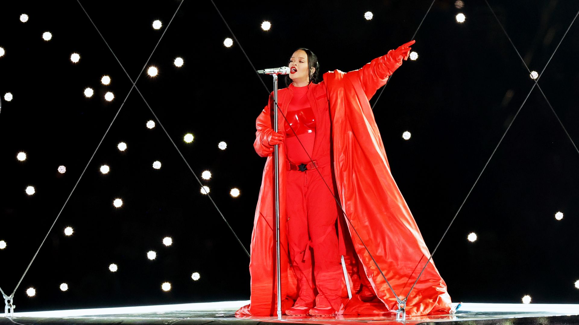 Rihanna sings into a microphone, wearing red from head to toe.