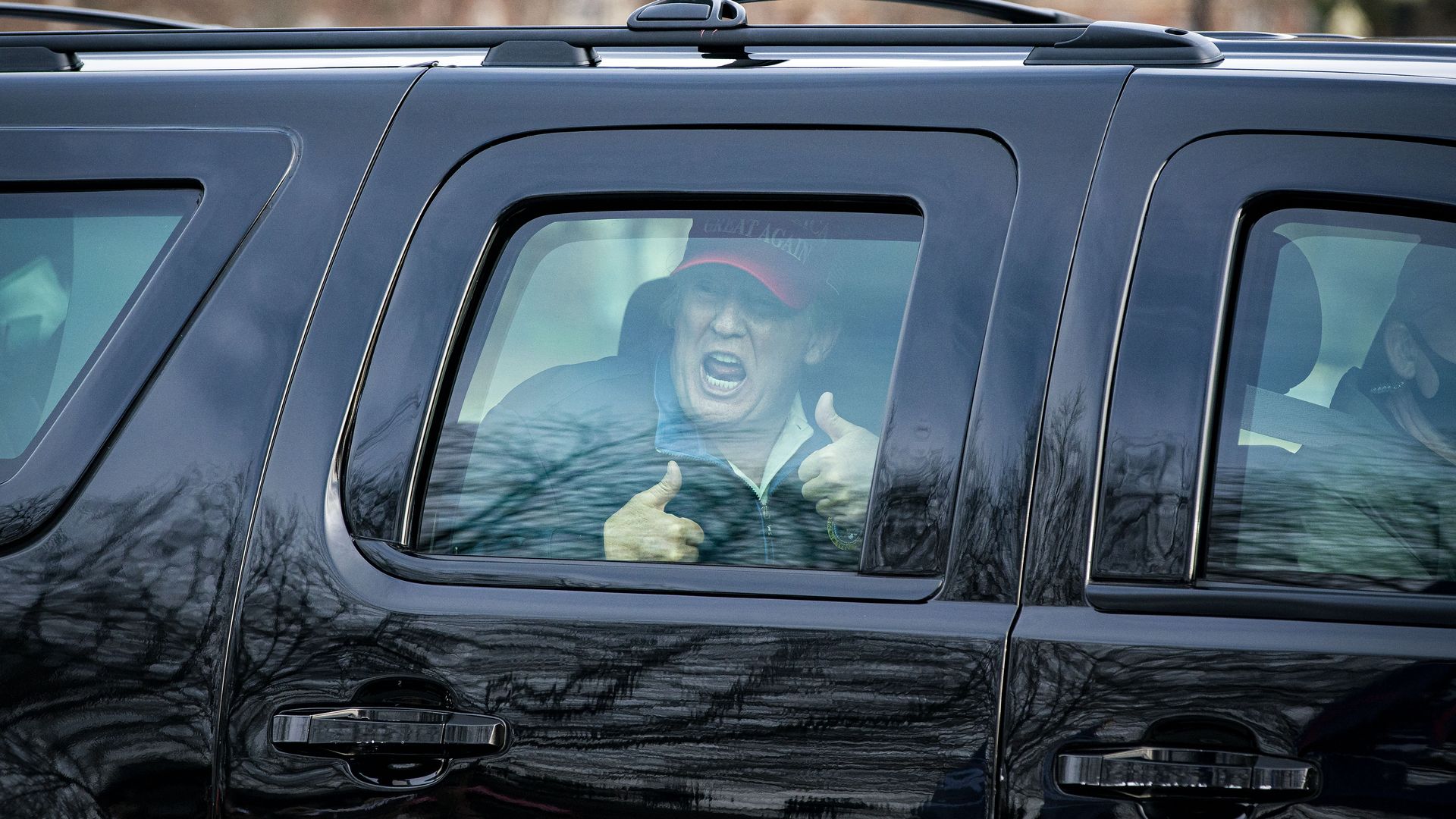 Trump gives a thumbs up through a car window
