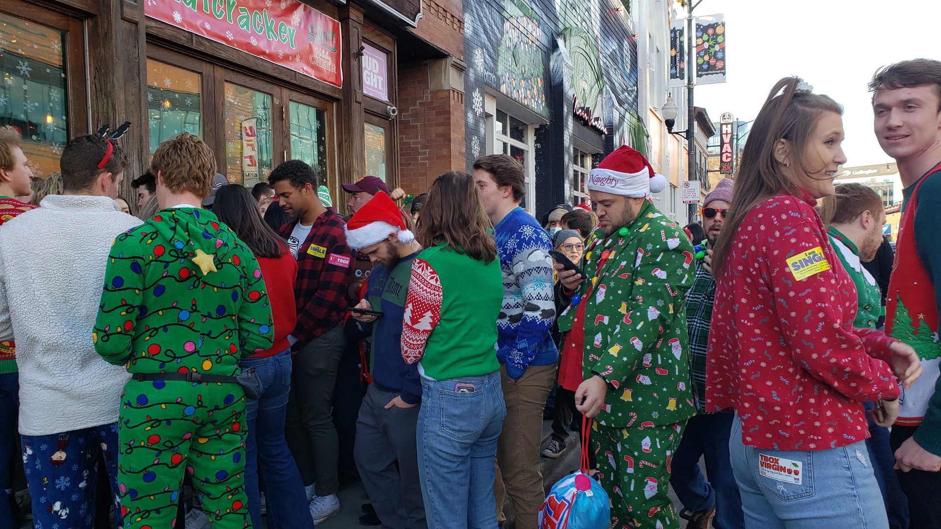 People crowded in Christmas pajamas in front of a bar. 