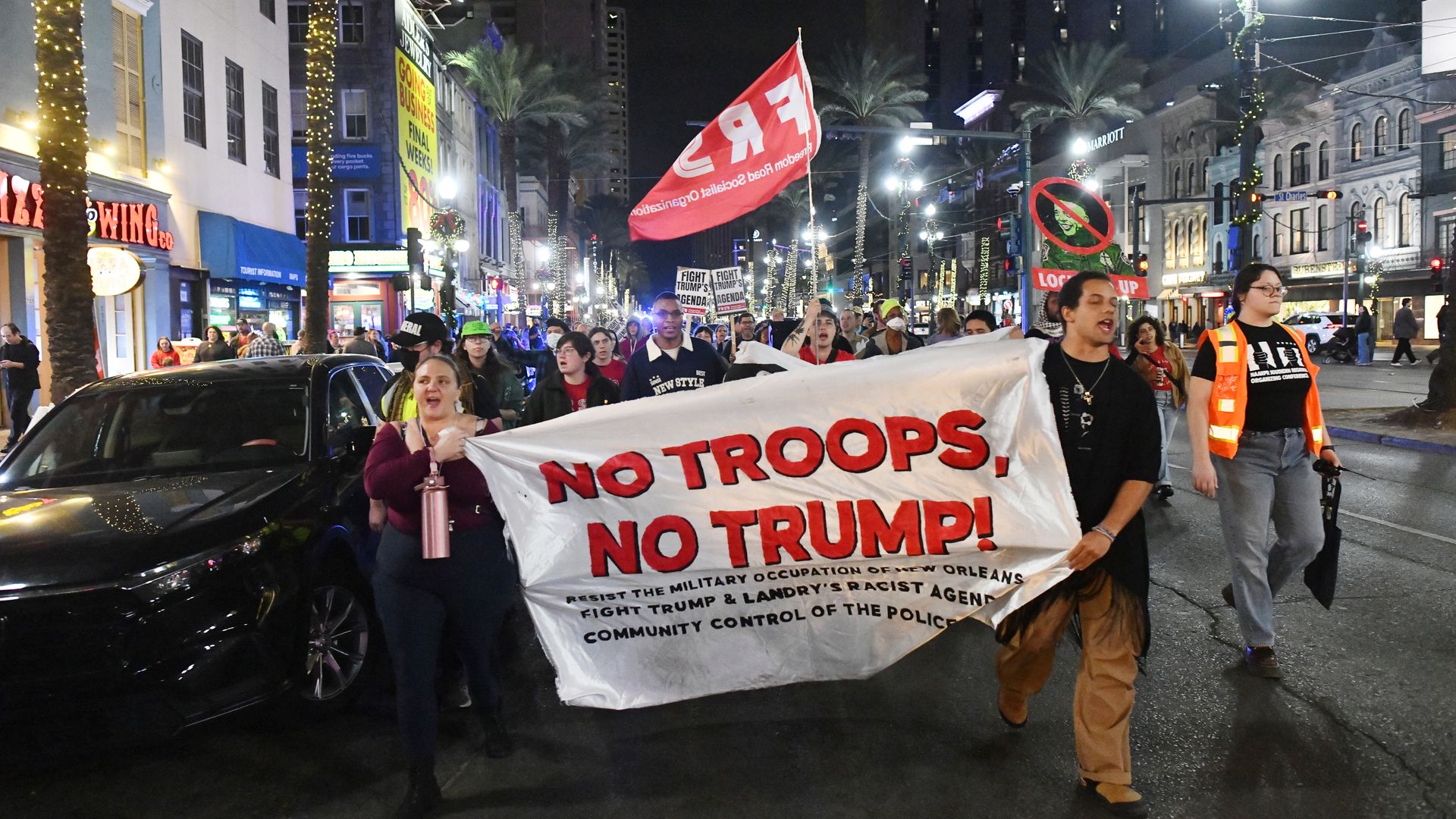 Image shows protestors on Canal Street holding a sign that says "No Troops, no Trump."