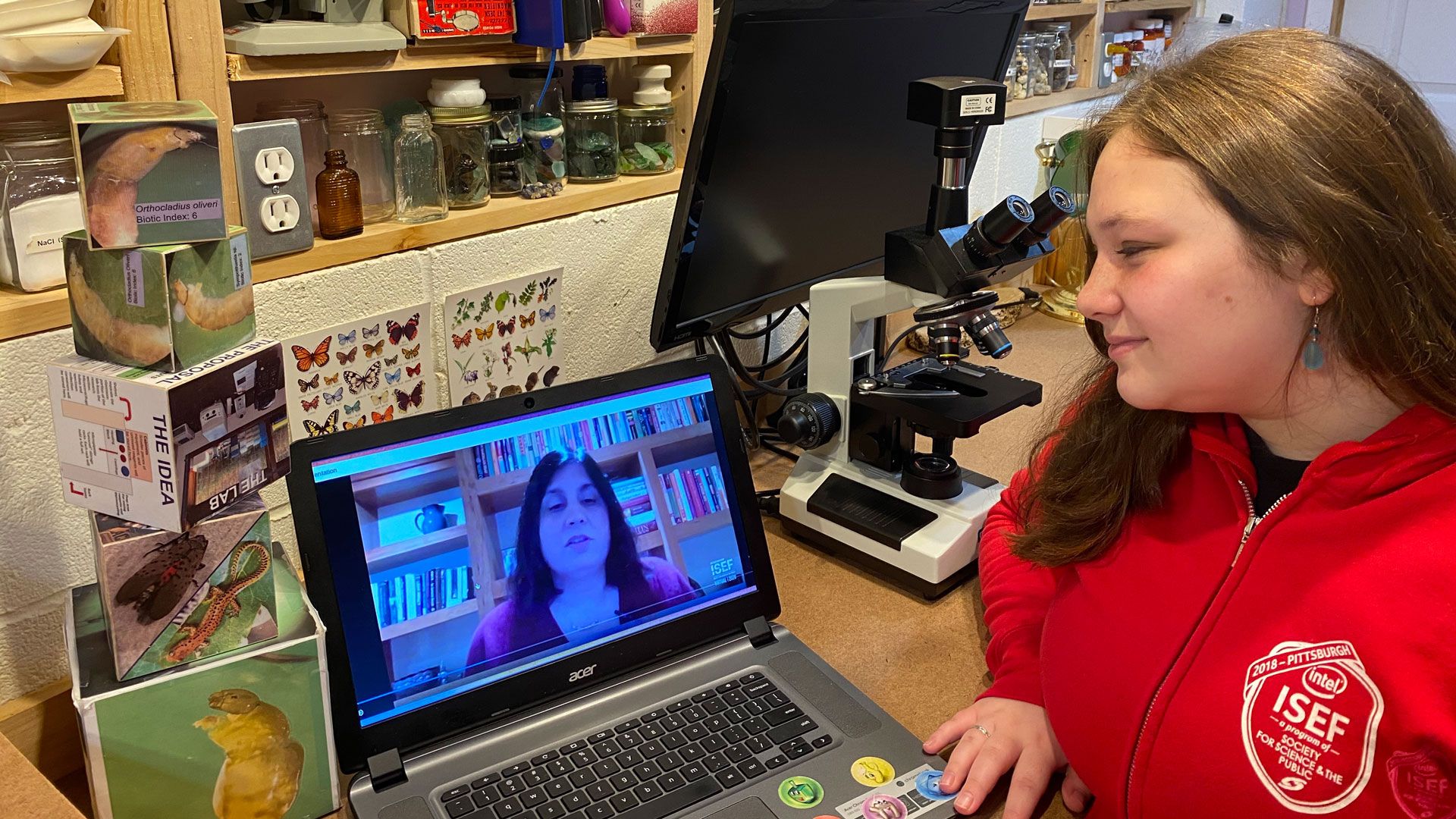 image of young person in a science classroom looking at a computer screen with a teacher