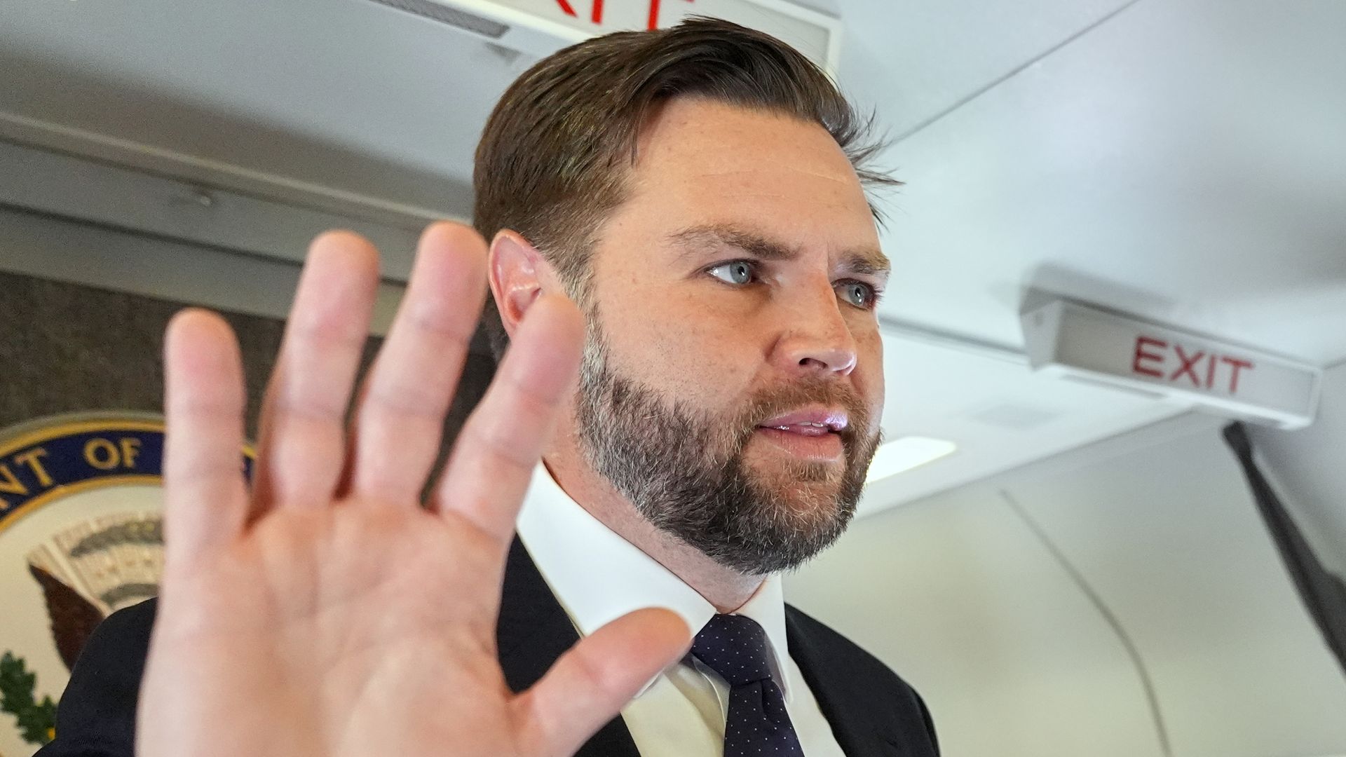 Vice President JD Vance holds up his hand as he talks to reporters (not pictured) aboard Air Force Two.