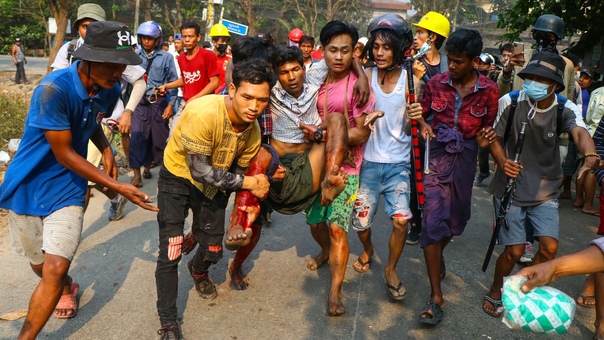 A resident, who was injured during a crackdown by security forces on demonstrations by protesters against the military coup, is carried to safety in Yangon's Hlaing Tharyar township on March 14