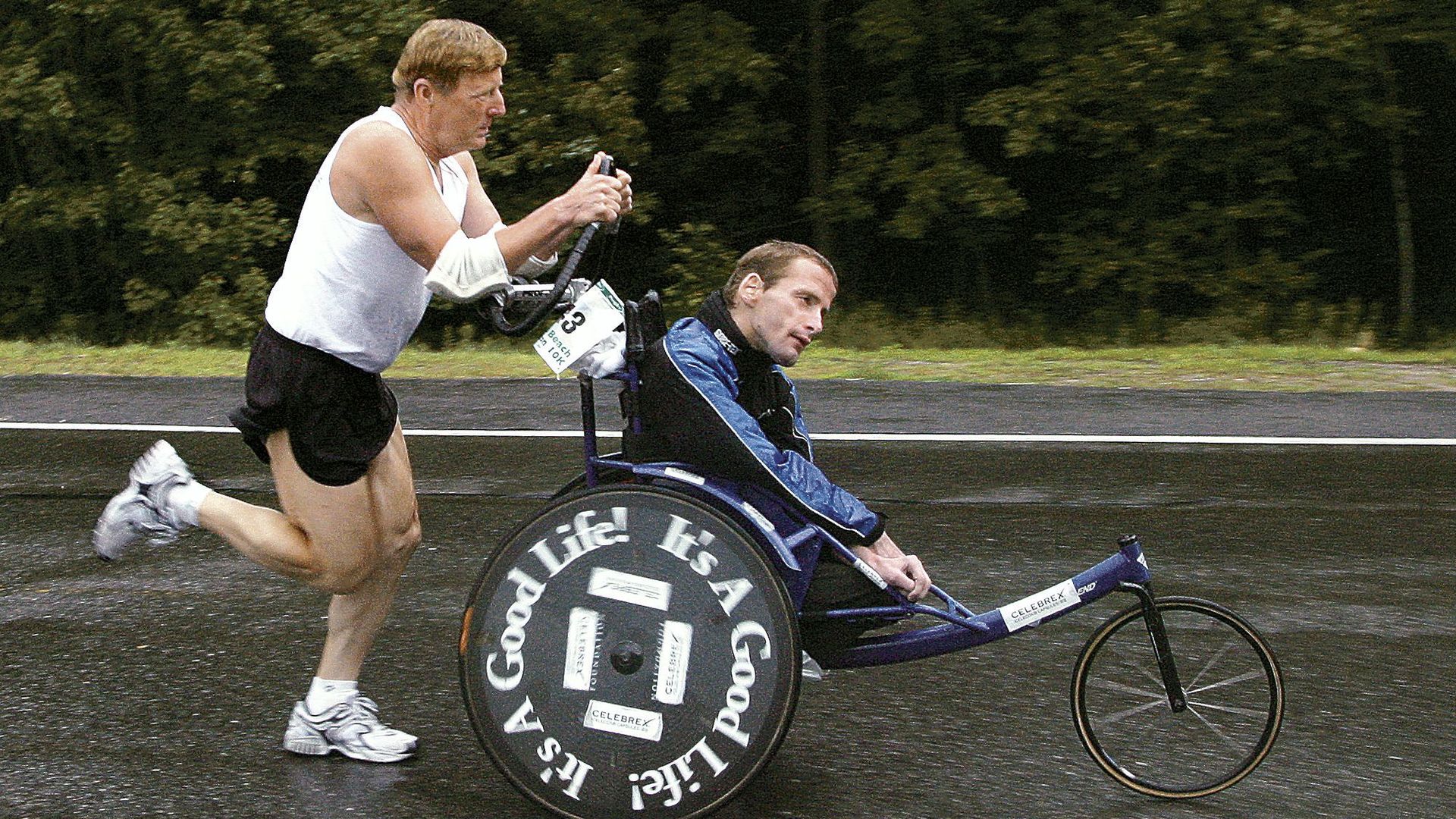 A man pushing a boy in a wheelchair. 
