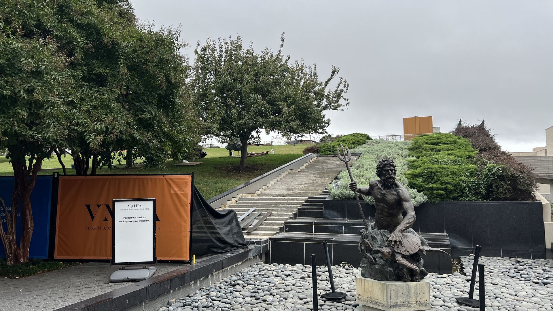 The VMFA lawn blocked off with a sign that says "pardon our dust as we improve your museum" and "danger construction area keep out." The stairs behind it are torn up and construction pieces scattered.
