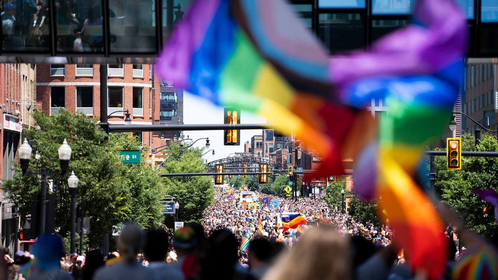 An overview of the Pride March with a flag in the foreground