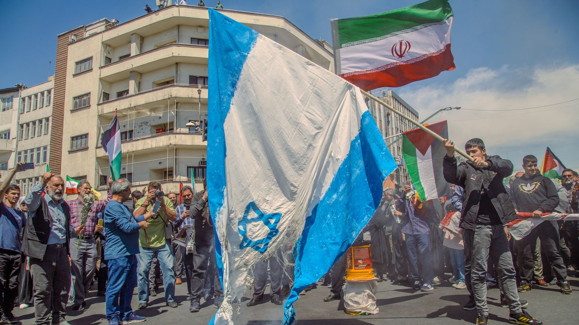 A damaged Israel flag and along with Iranian and Palestinian flags held by Iranian demonstrators in  Tehran on April 5.