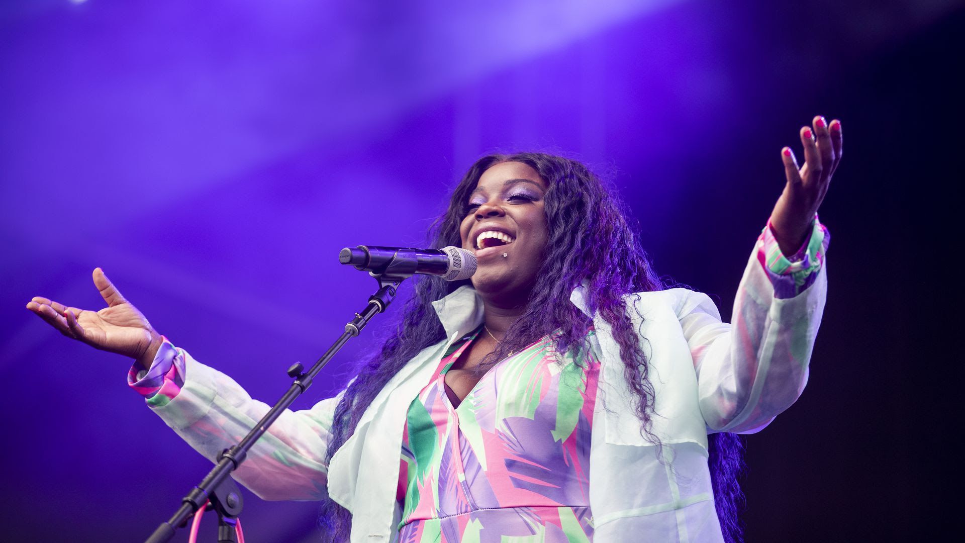 Yola sings on stage in front of a microphone.