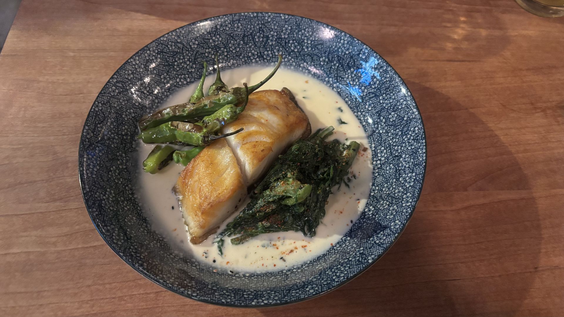 A black cod dish served with vegetables and greens.