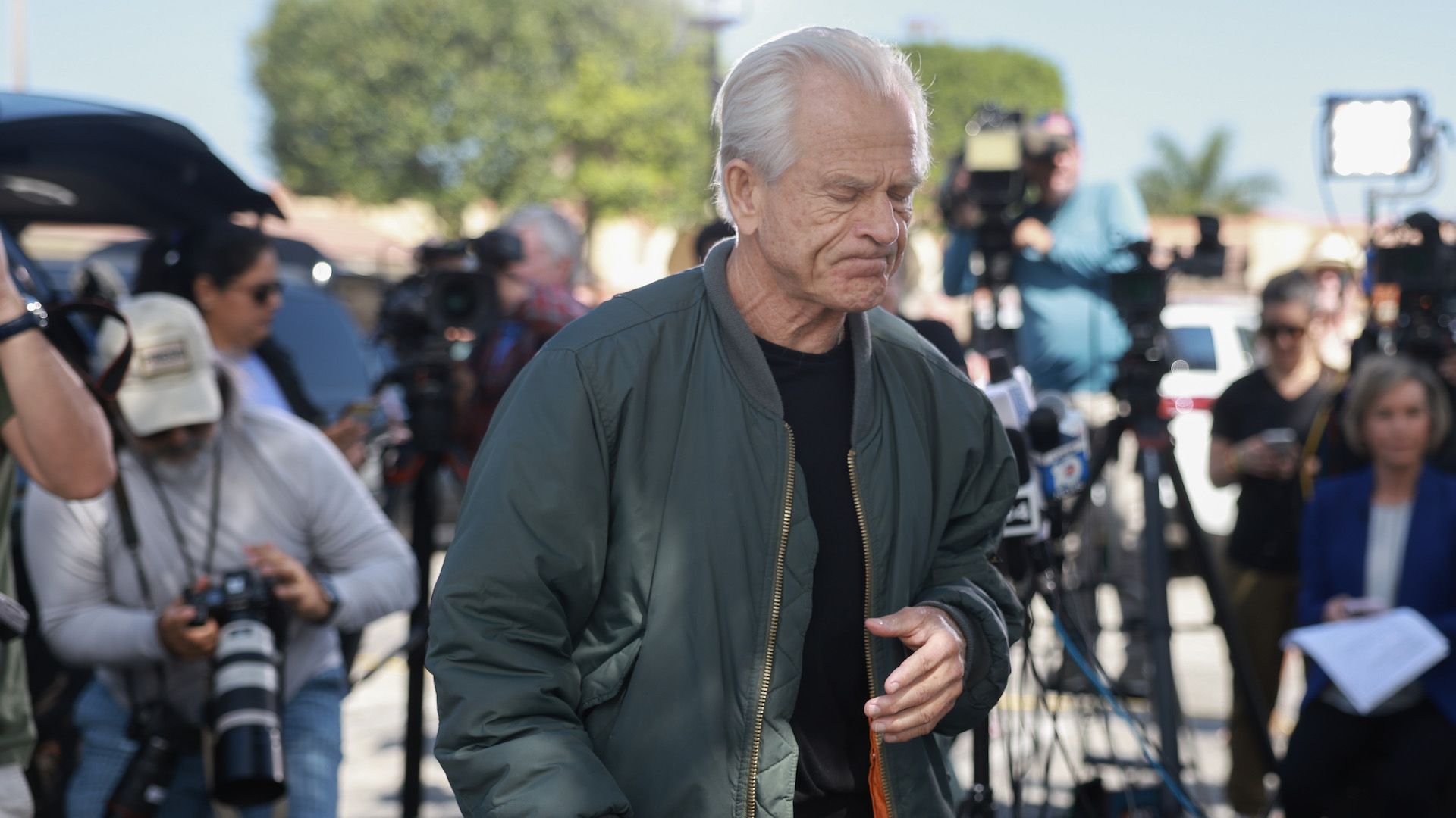 Former President Trump adviser Peter Navarro walks through a crown of reporters.