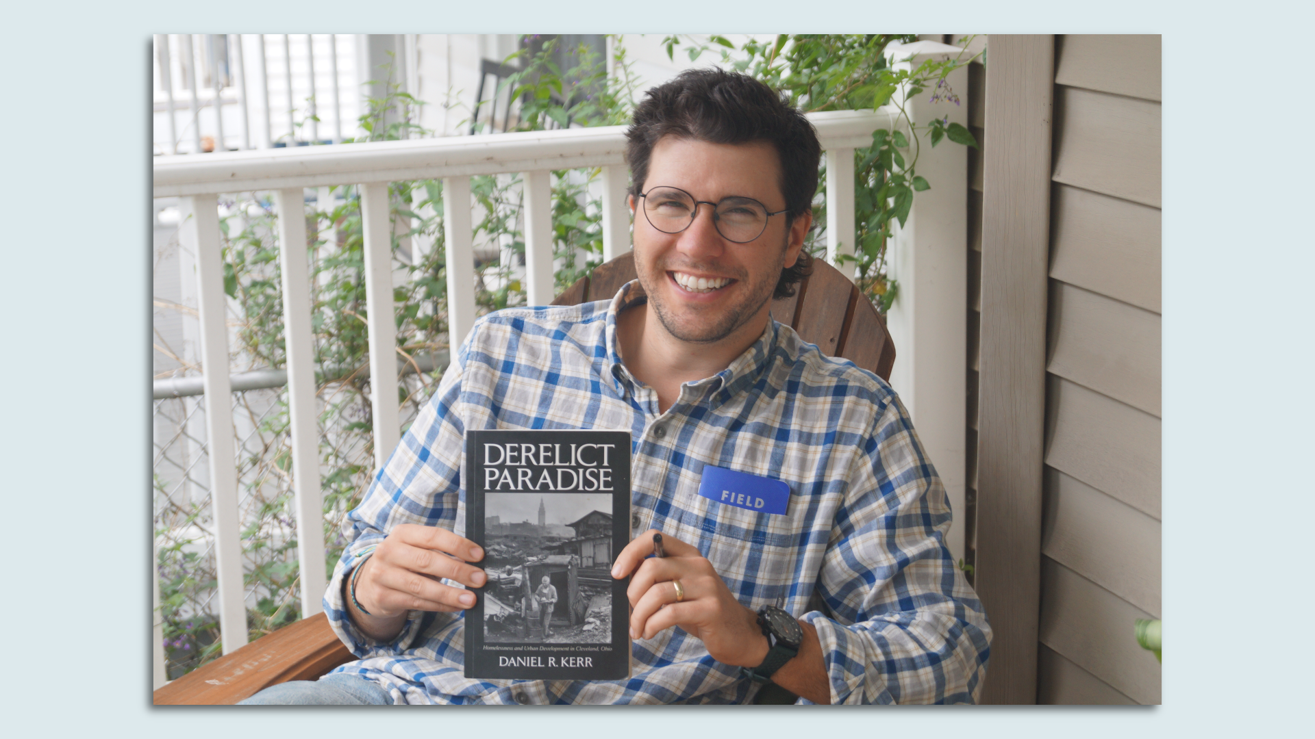 Sam Allard holds a copy of the book Derelict Paradise