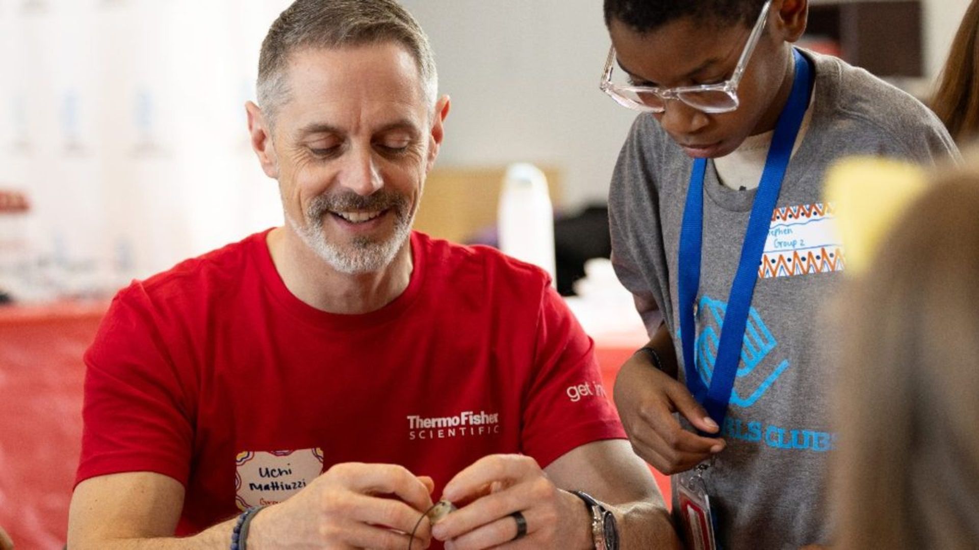 A Thermo Fisher Scientific volunteer helps a Boys & Girls Club member with a hands-on activity, highlighting STEM engagement and mentorship.