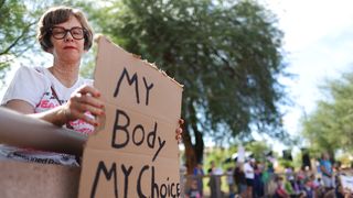 A protester holds a sign reading 'My Body My Choice' at a Women's March rallyoutside the State Capitol on October 8, 2022 in Phoenix, Arizona. 