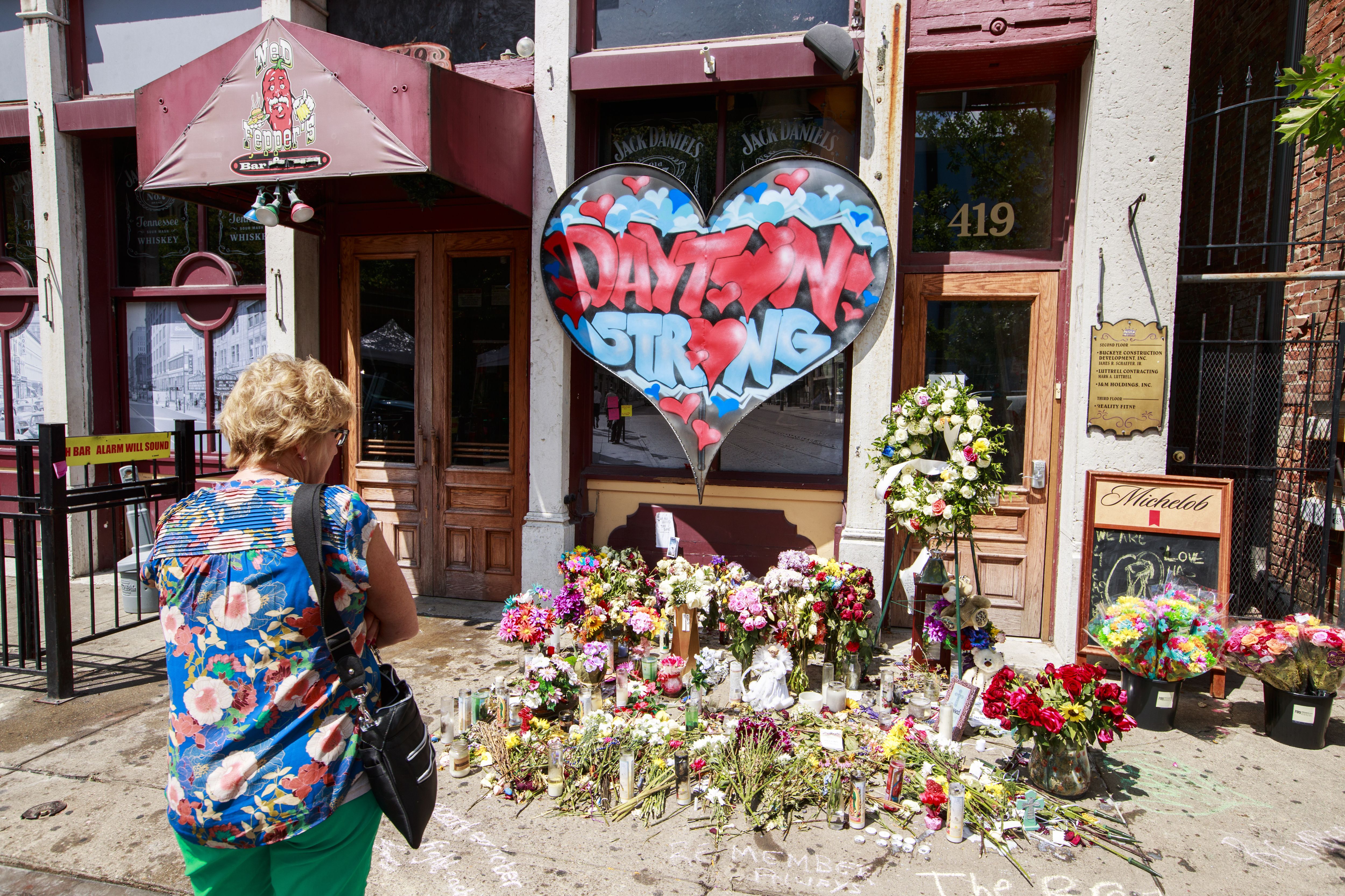  A woman stops to look at a memorial on 5th Street at the site of Sunday morning's mass shooting 