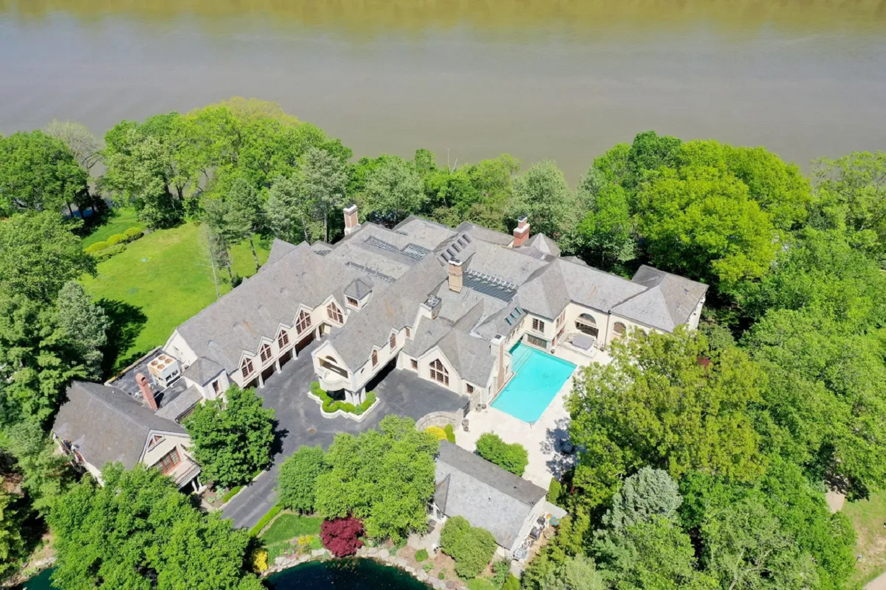 A birds-eye view of a large riverfront mansion. 