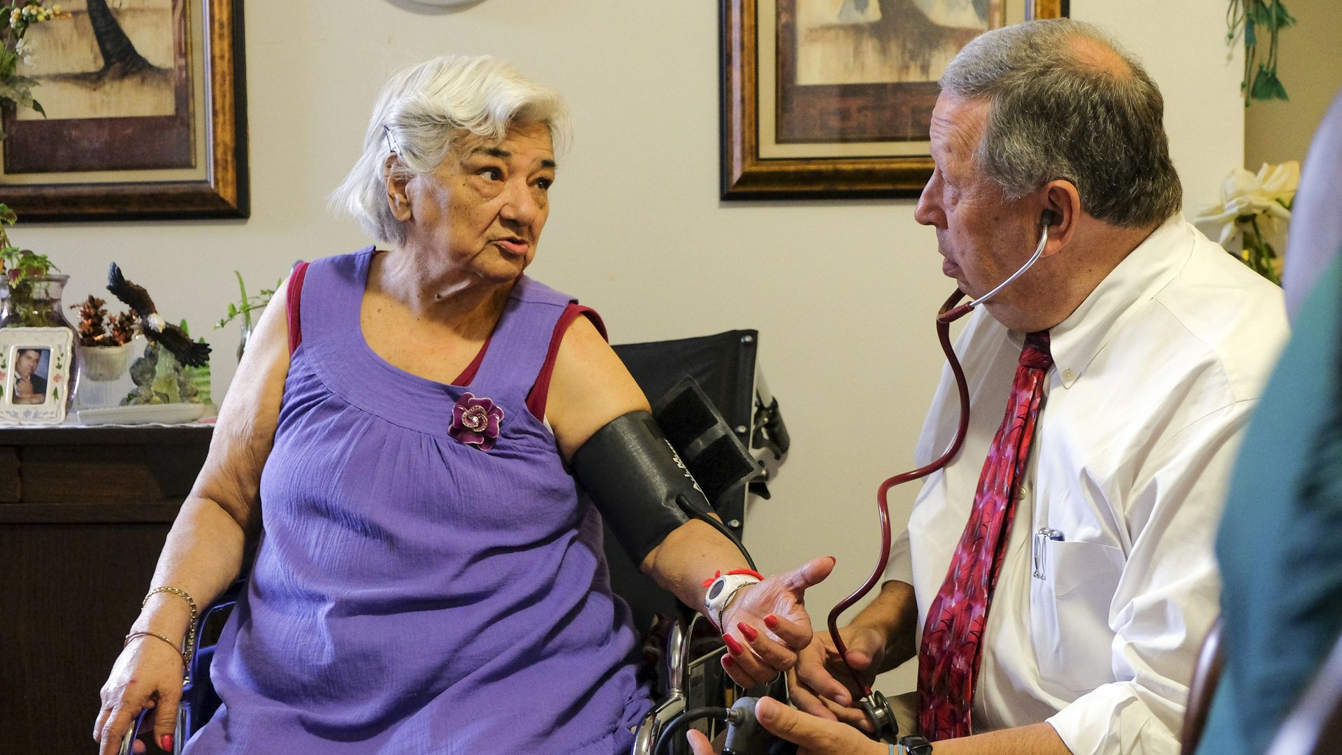 An elderly woman sees a doctor for a checkup in her home.