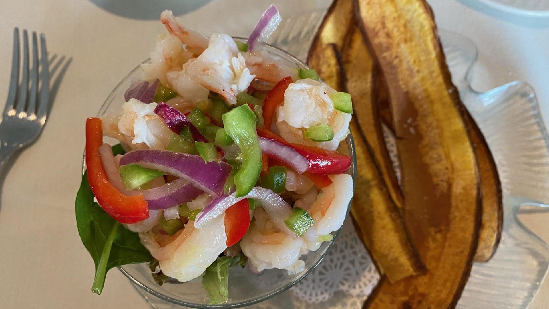 a glass of ceviche and long strips of fried plaintains