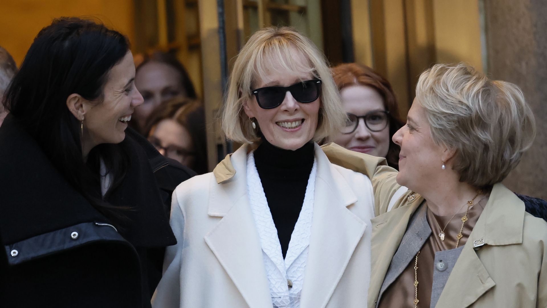 E. Jean Carroll, wearing a white coat and sunglasses