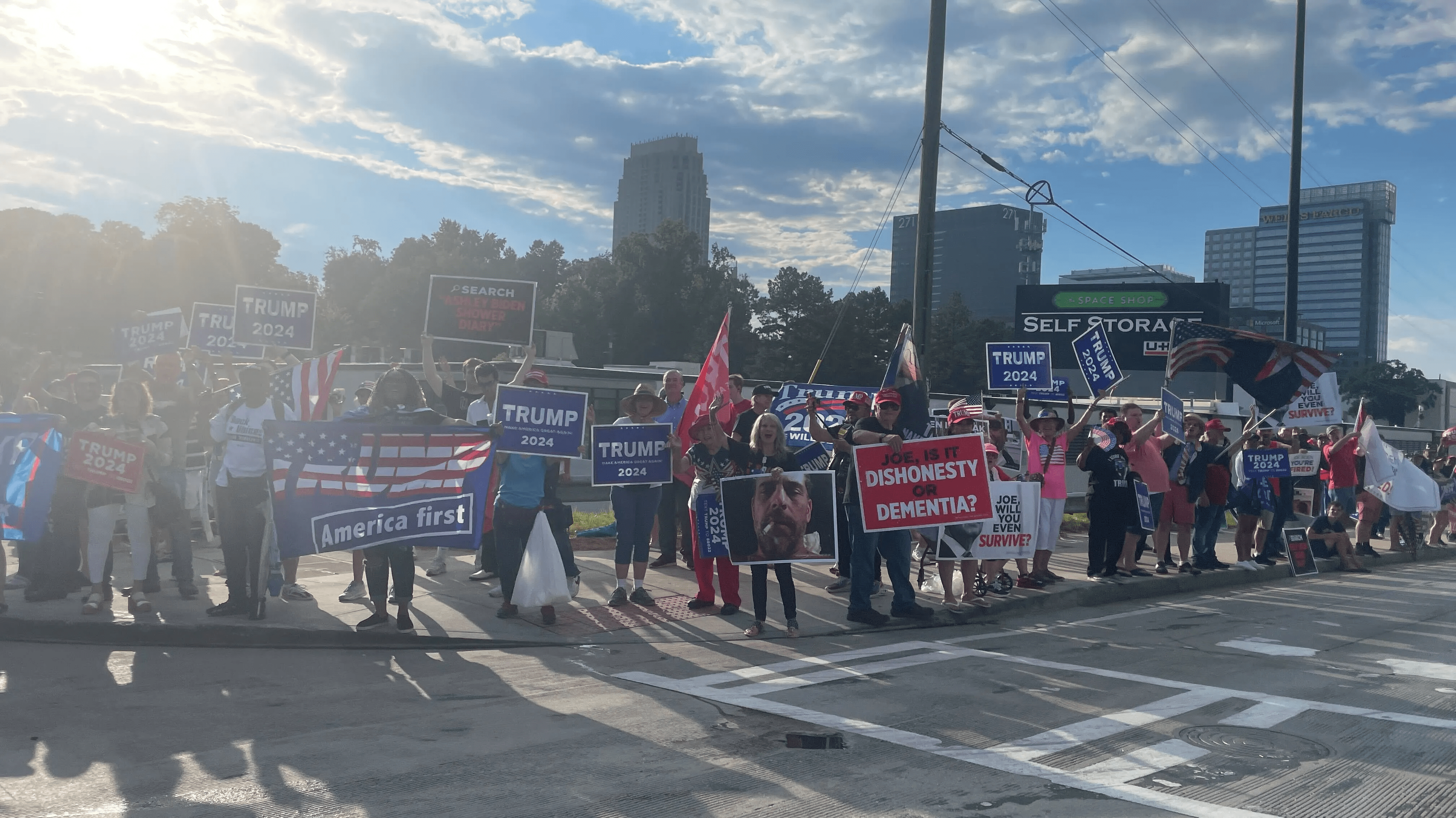 A crowd of Trump supporters is gathering near the debate site, waving flags and holding signs.