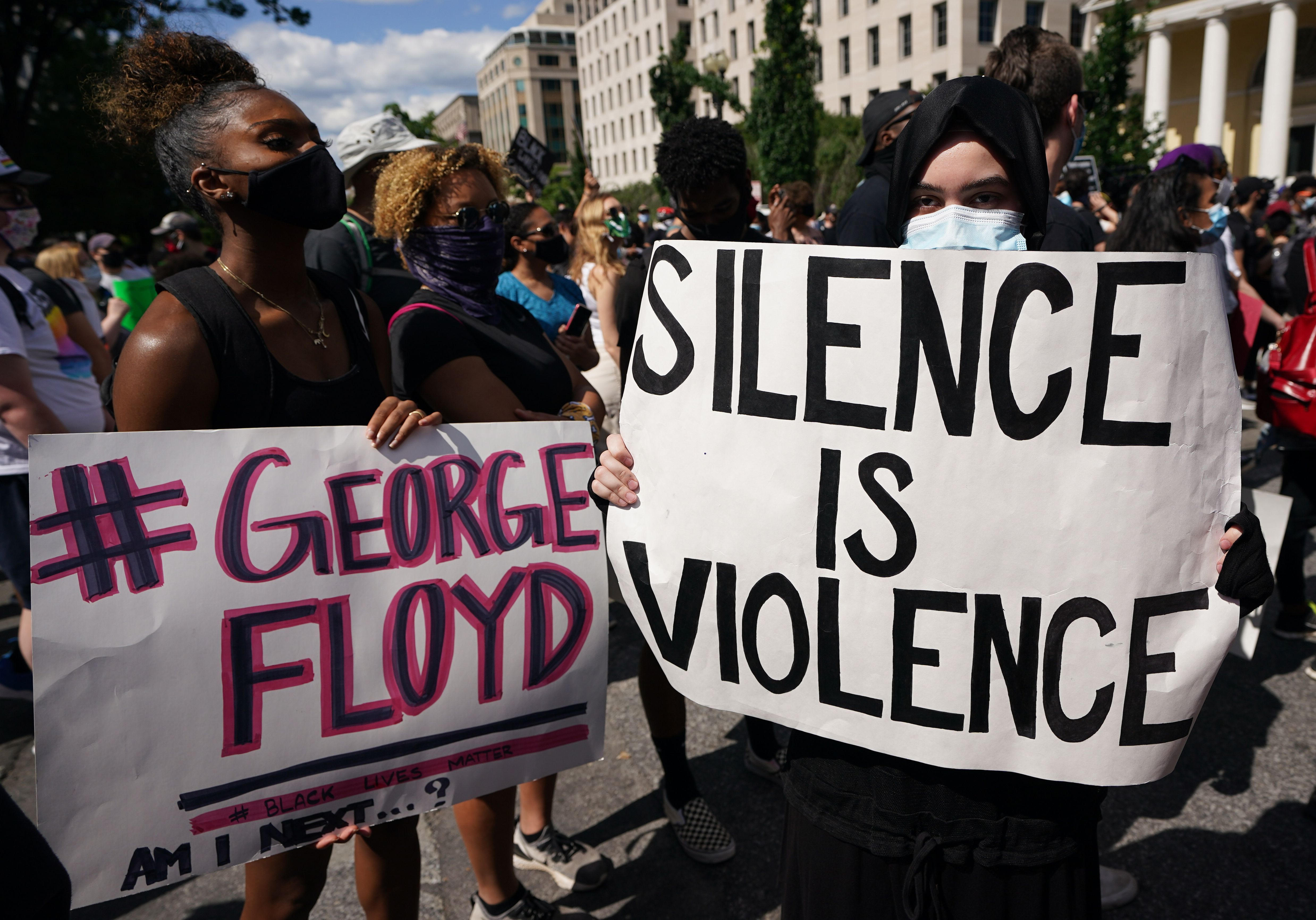 People protesting the death of George Floyd hold up placards in a street near the White House on May 31, 2020 in Washington, DC. 