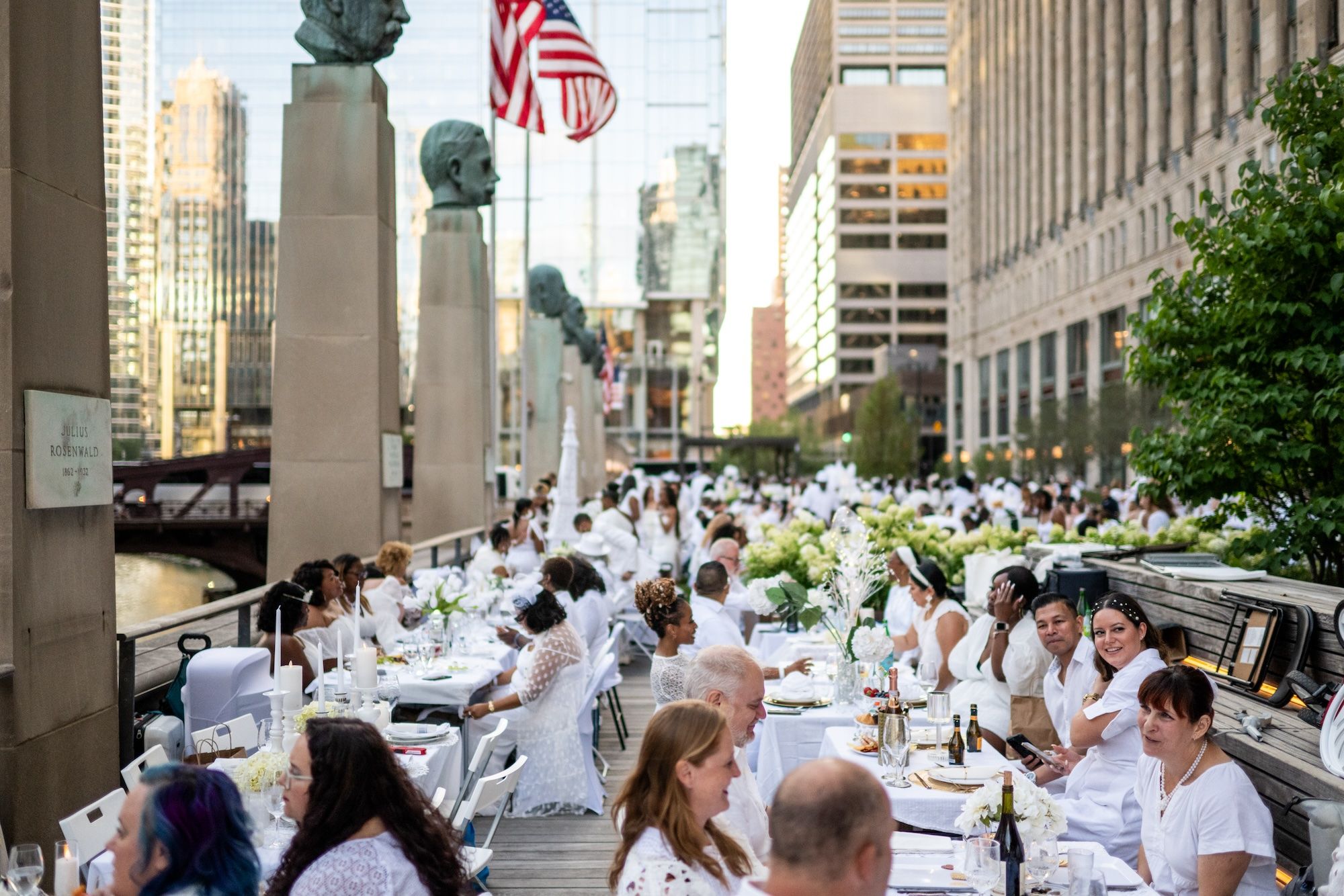 Rows of diners wearing white sitting at white table-clothed tables.