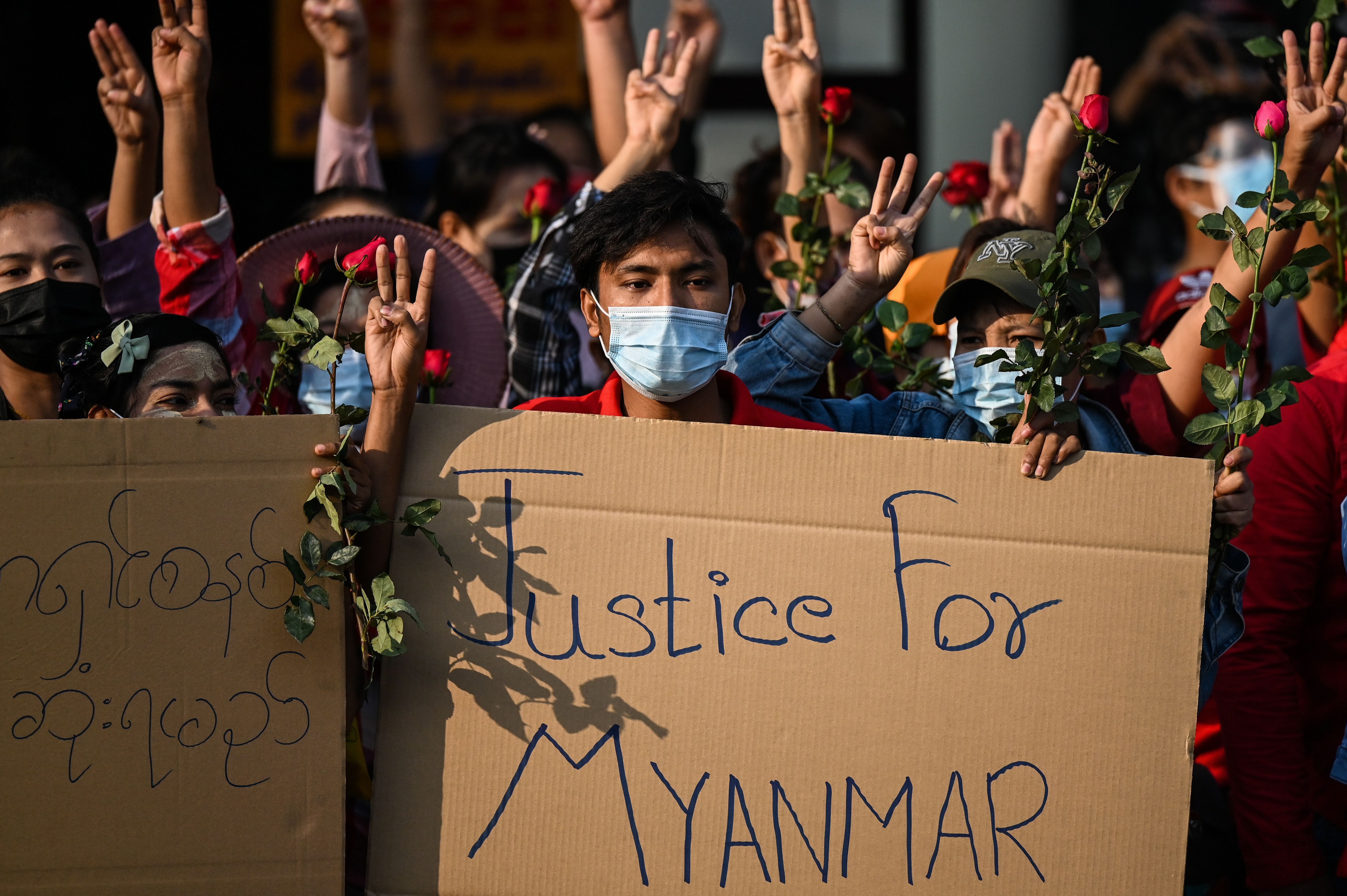  Protesters hold placards and flowers during a demonstration against the military coup in Yangon on February 7