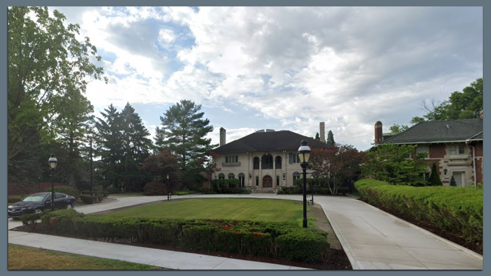 The home with a huge driveway, manicured lawn and stately facade with small columns and artistic touches